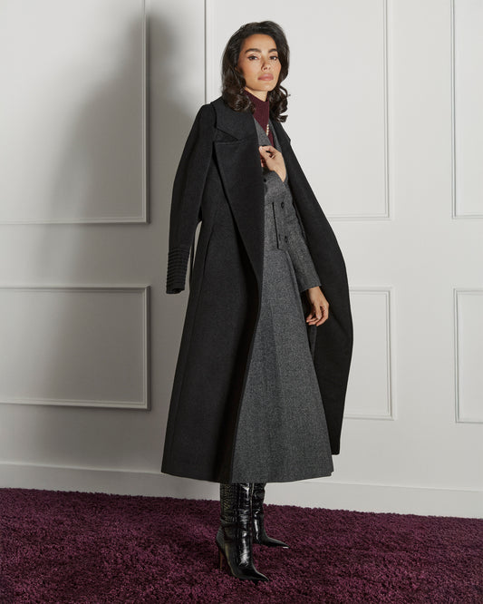Side view of model wearing a SENTALER long black wrap coat made of baby alpaca wool, with a large notched collar, worn open.