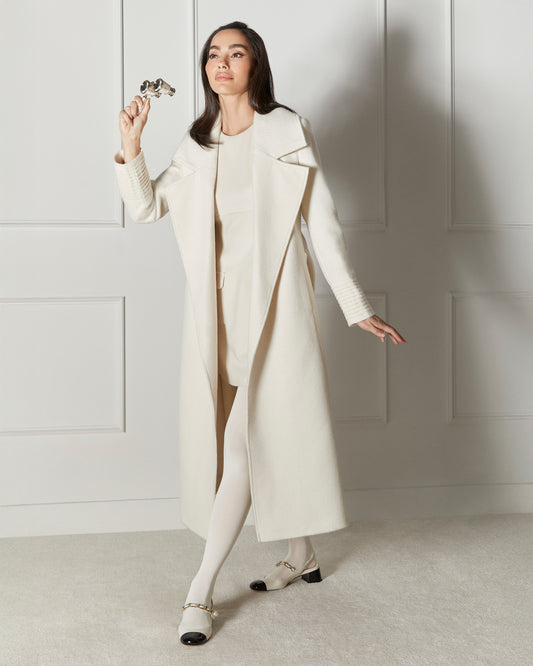 Side view of model wearing a SENTALER long ivory wrap coat made of baby alpaca wool, with a large notched collar, worn open.