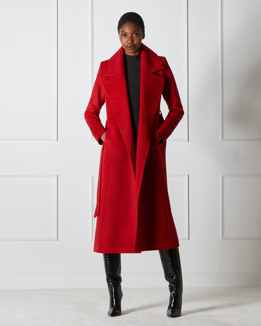 Direction view of model wearing a SENTALER long scarlet red wrap coat made of baby alpaca wool, with a large notched collar, worn open.