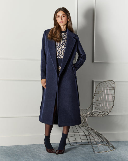 Front view of model wearing a Sentaler long deep navy wrap coat made of baby alpaca wool, with a notched collar, worn open.