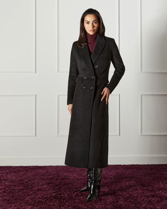Front view of model wearing a Sentaler black double breasted maxi coat made of baby alpaca wool, with a peak collar, worn buttoned.