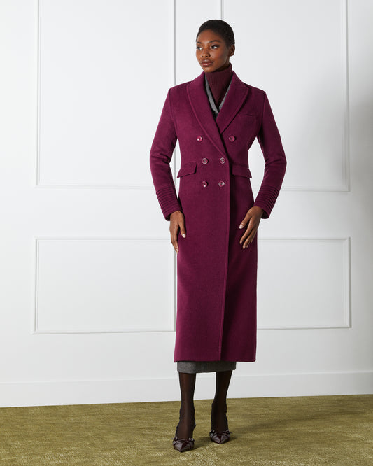Front view of model wearing a Sentaler cherry lacquer double breasted maxi coat made of baby alpaca wool, with a peak collar, worn buttoned.