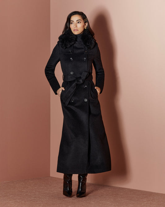 Front view of model in Sentaler maxi black trench coat made of baby alpaca wool with shearling collar, buttoned & belted.