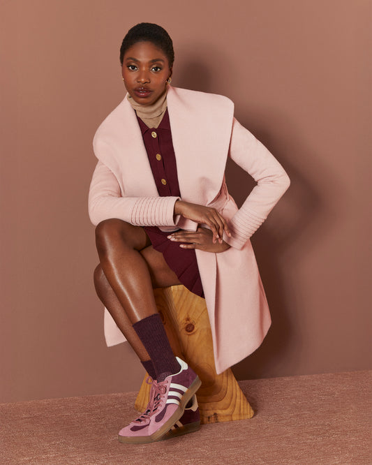 Front view of model wearing a Sentaler mid length blush pink coat made of baby alpaca wool, with a shawl collar, worn open.