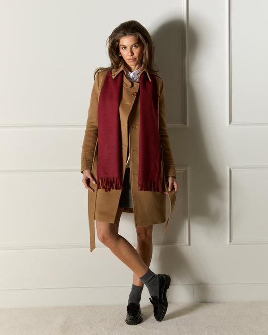 Front view of model wearing a Sentaler mid length dark camel trench coat made of baby alpaca wool, with a spread collar, worn open.