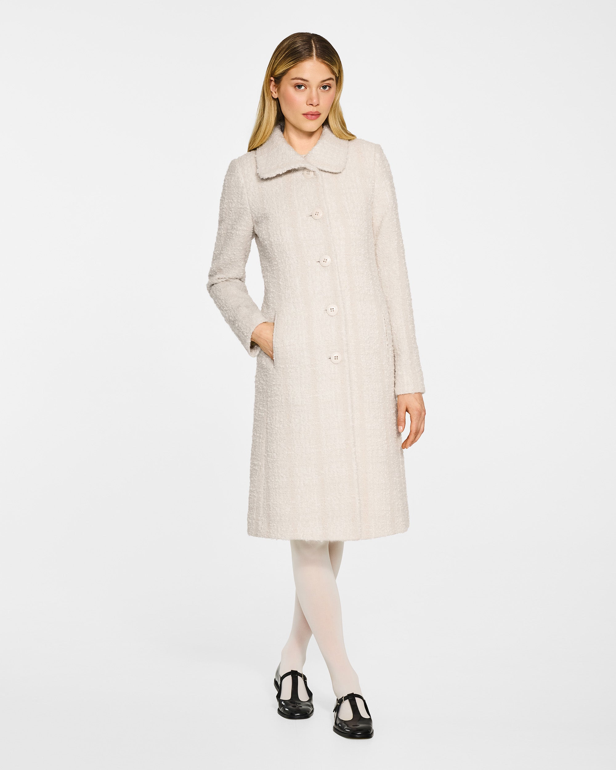 Front view of model wearing a Sentaler ivory glittered A-line coat made of tweed suri alpaca wool, worn buttoned.