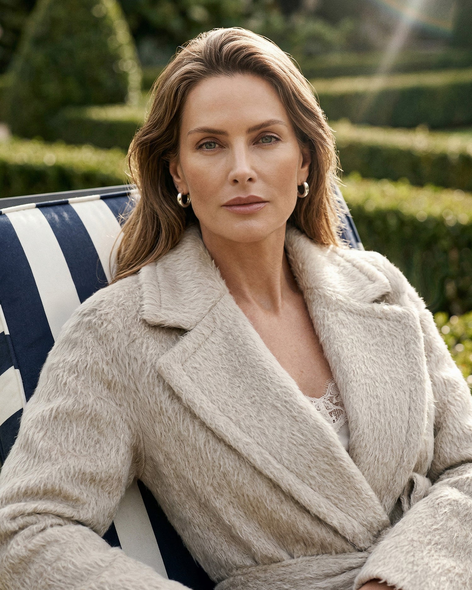Front view of model wearing a Sentaler oat coat made of suri alpaca wool, with raglan sleeves, worn belted.