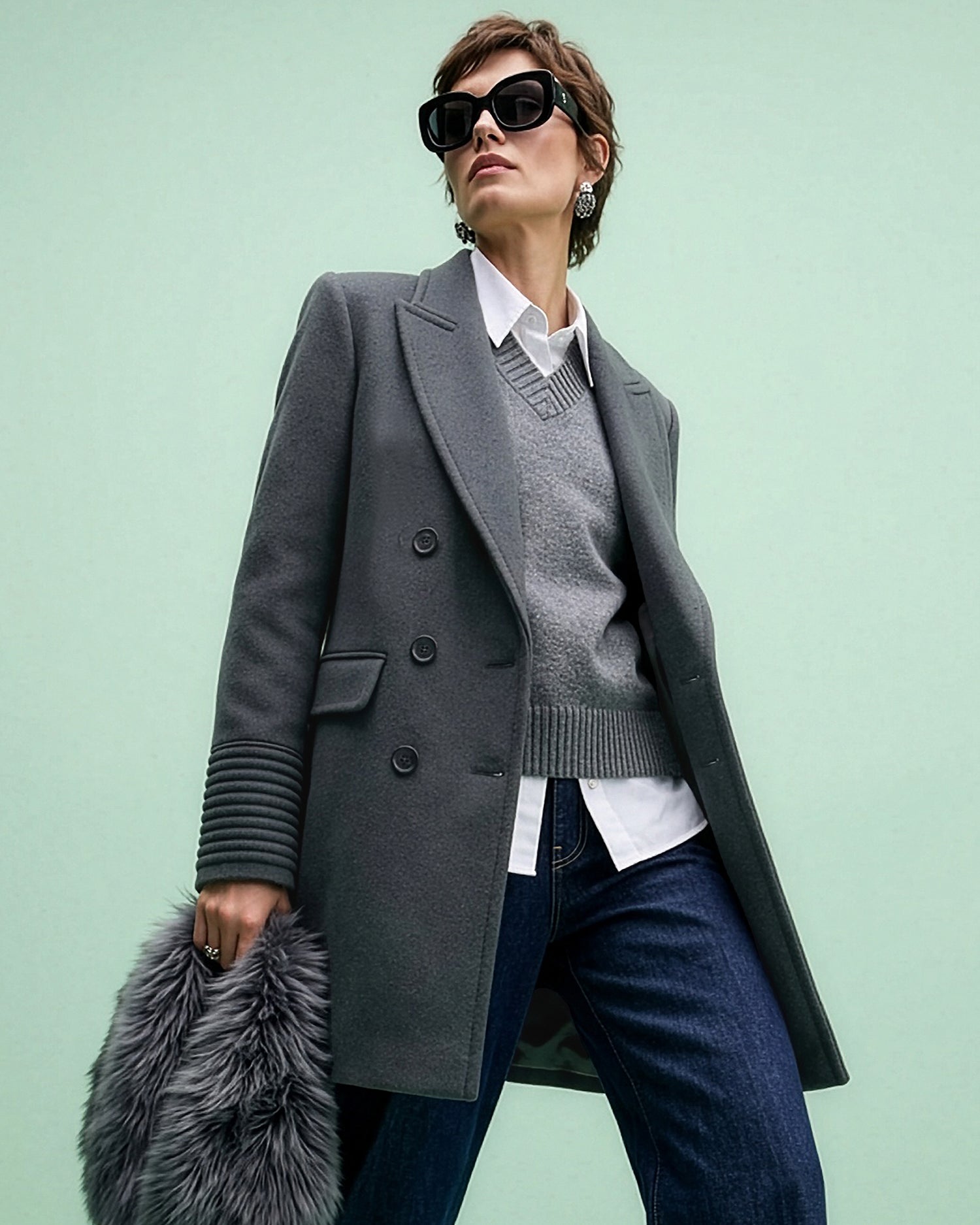 Front view of model wearing a Sentaler graphite topcoat made of baby alpaca wool, with a peak collar, worn unbuttoned with shearling collar in hand.