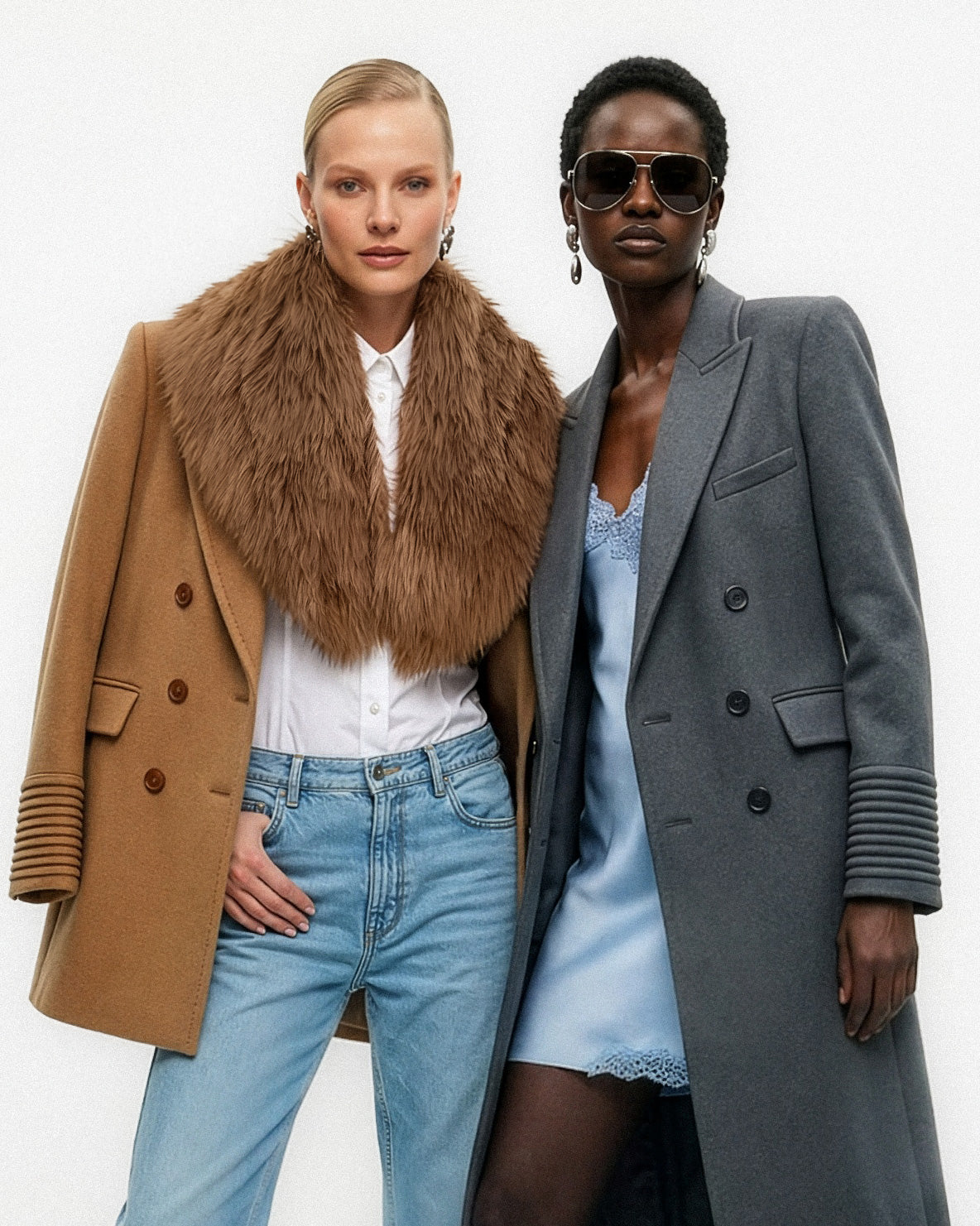 Front view of models wearing a Sentaler dark camel topcoat made of baby alpaca wool, with a peak collar, worn unbuttoned with shearling collar, and a Sentaler graphite double breasted maxi coat made of baby alpaca wool, with a peak collar, worn unbuttoned.