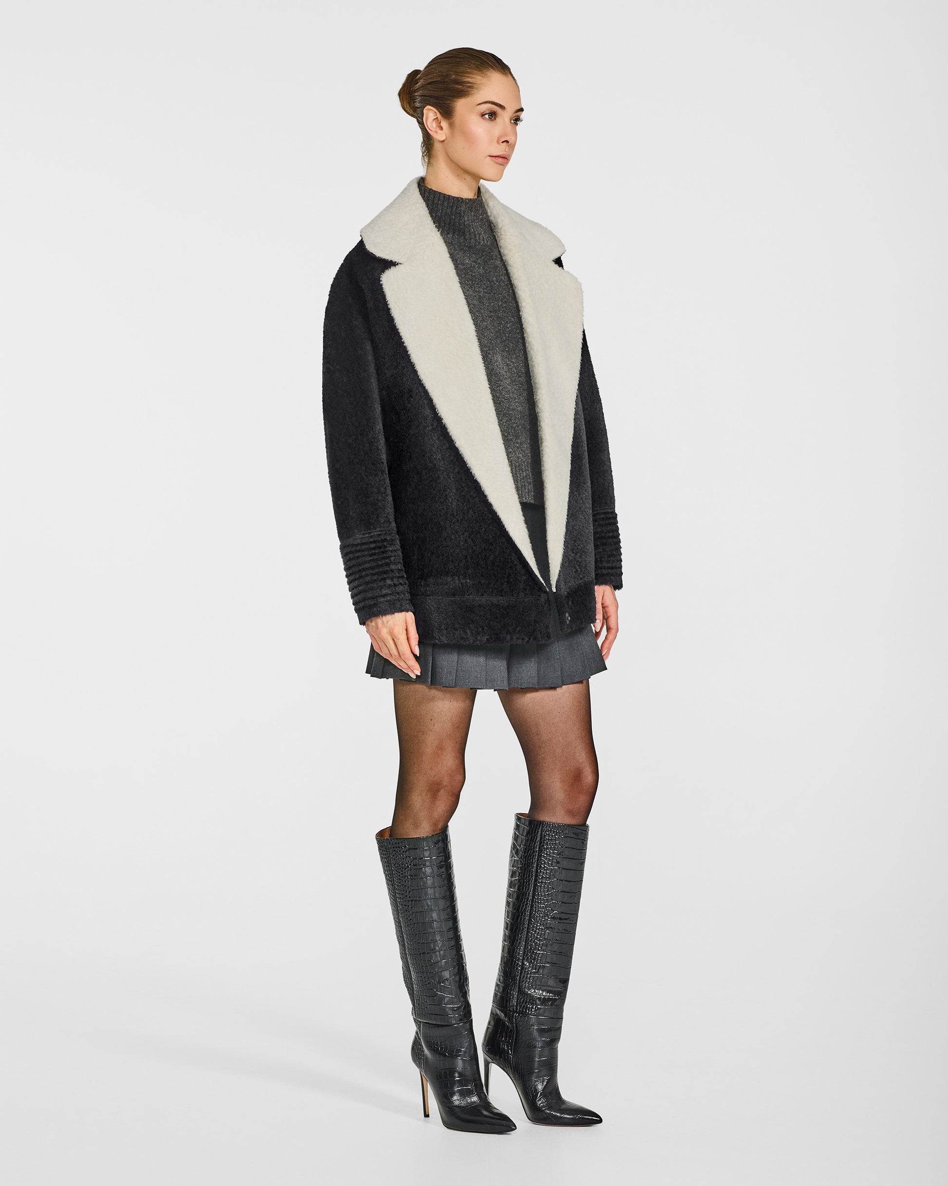 Side view of model in Sentaler black and white aviator jacket with dropped shoulders in bouclé alpaca wool, open.