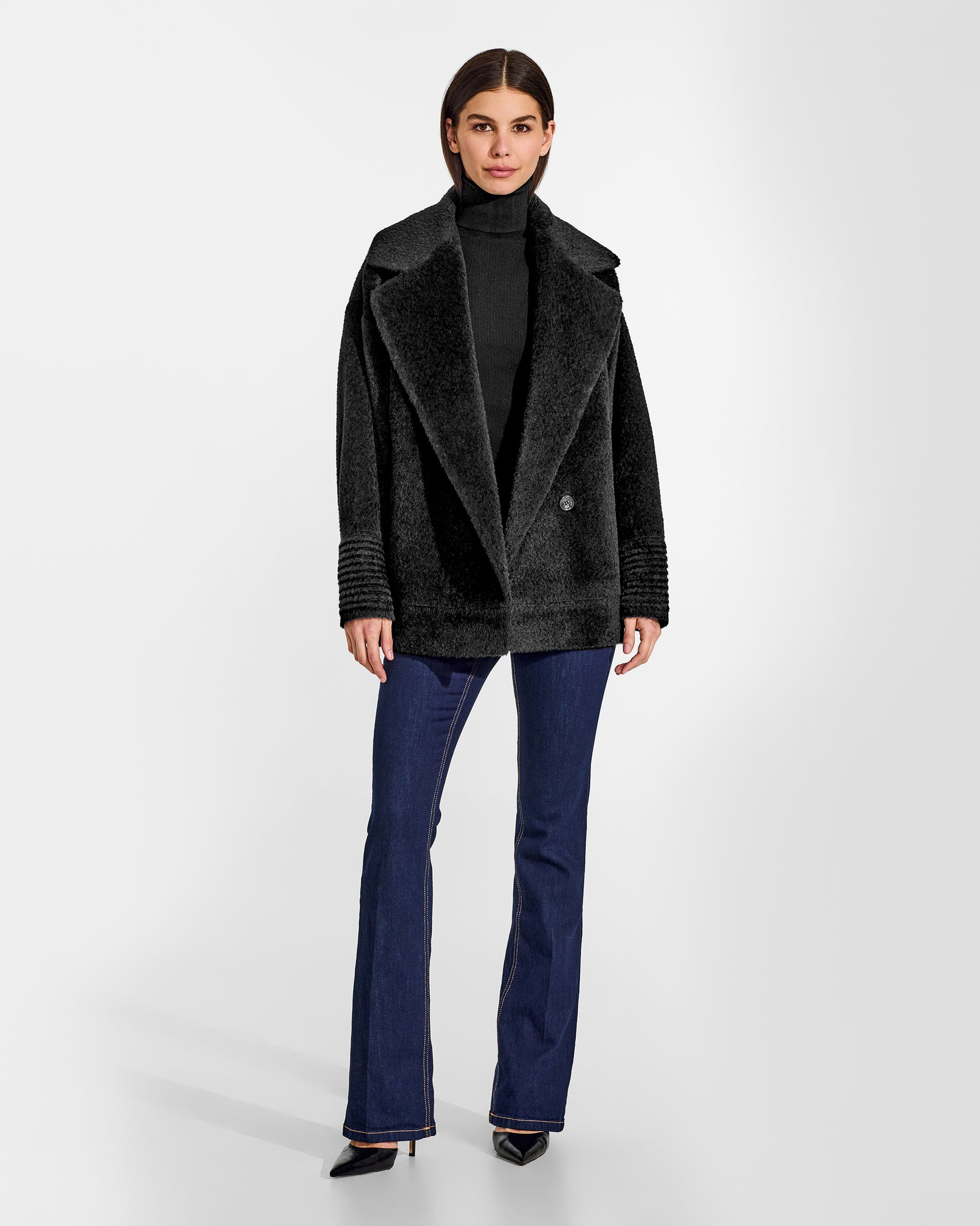 Front view of model wearing a Sentaler black aviator jacket made of bouclé alpaca wool, with dropped shoulders, worn buttoned.