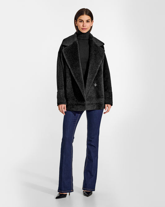 Front view of model wearing a Sentaler black aviator jacket made of bouclé alpaca wool, with dropped shoulders, worn buttoned.