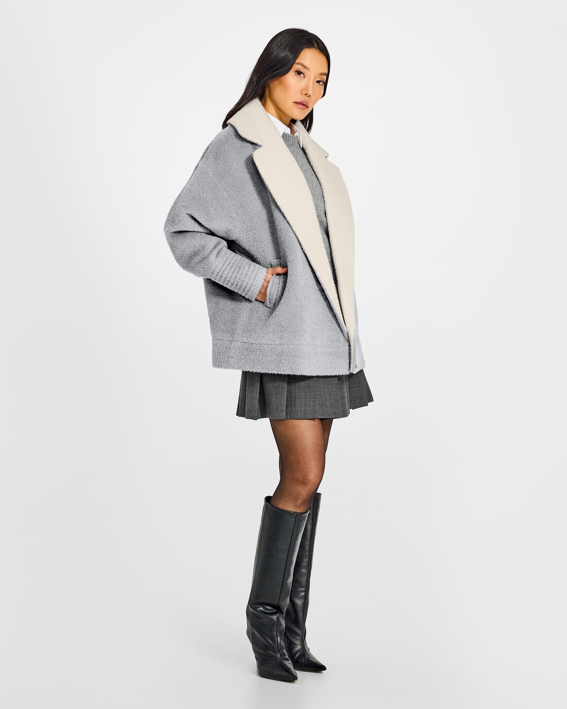 Side view of model wearing a Sentaler glacial grey aviator jacket made of bouclé alpaca wool, with dropped shoulders, worn open.