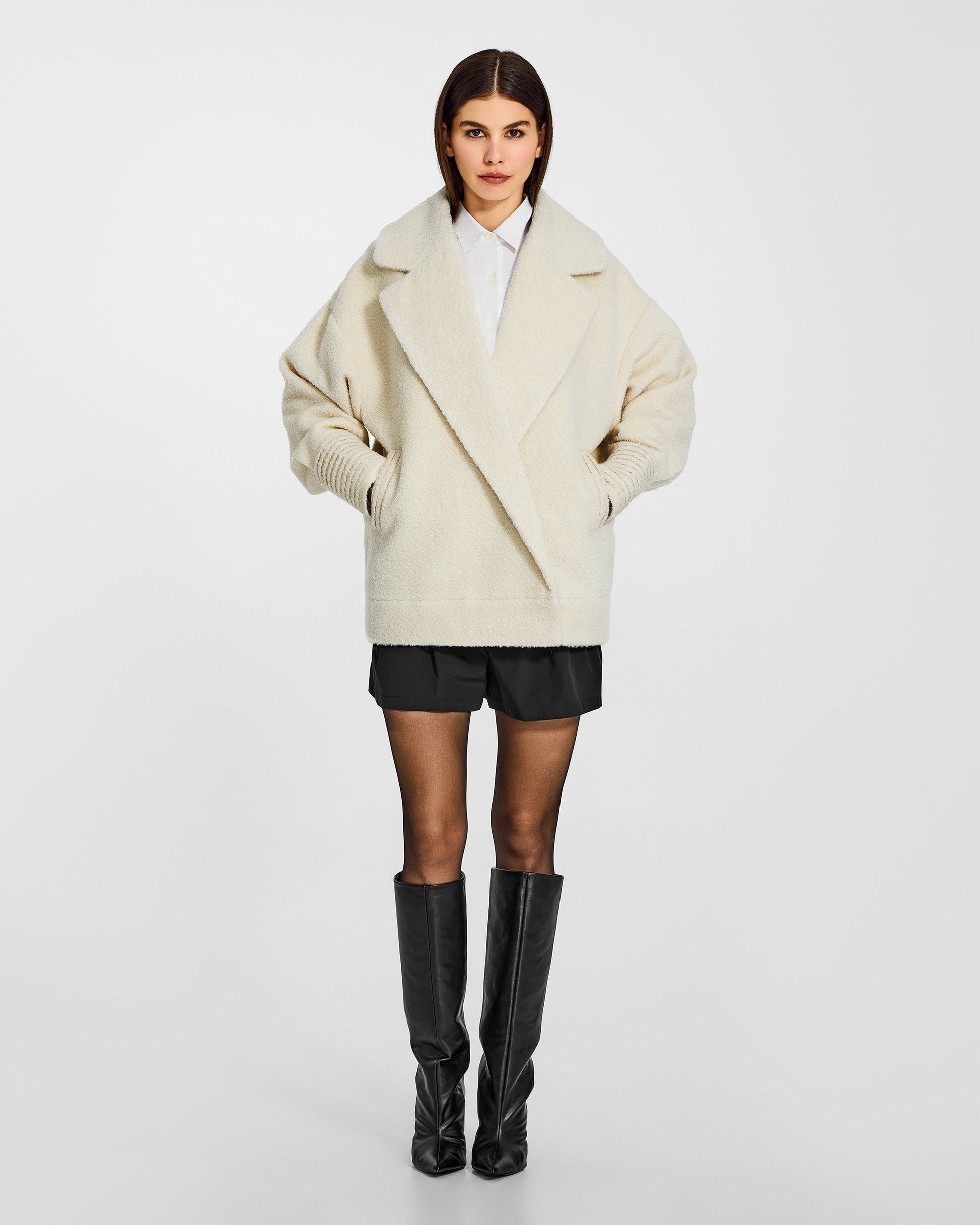 Front view of model wearing a Sentaler ivory aviator jacket made of bouclé alpaca wool, with dropped shoulders, worn buttoned.