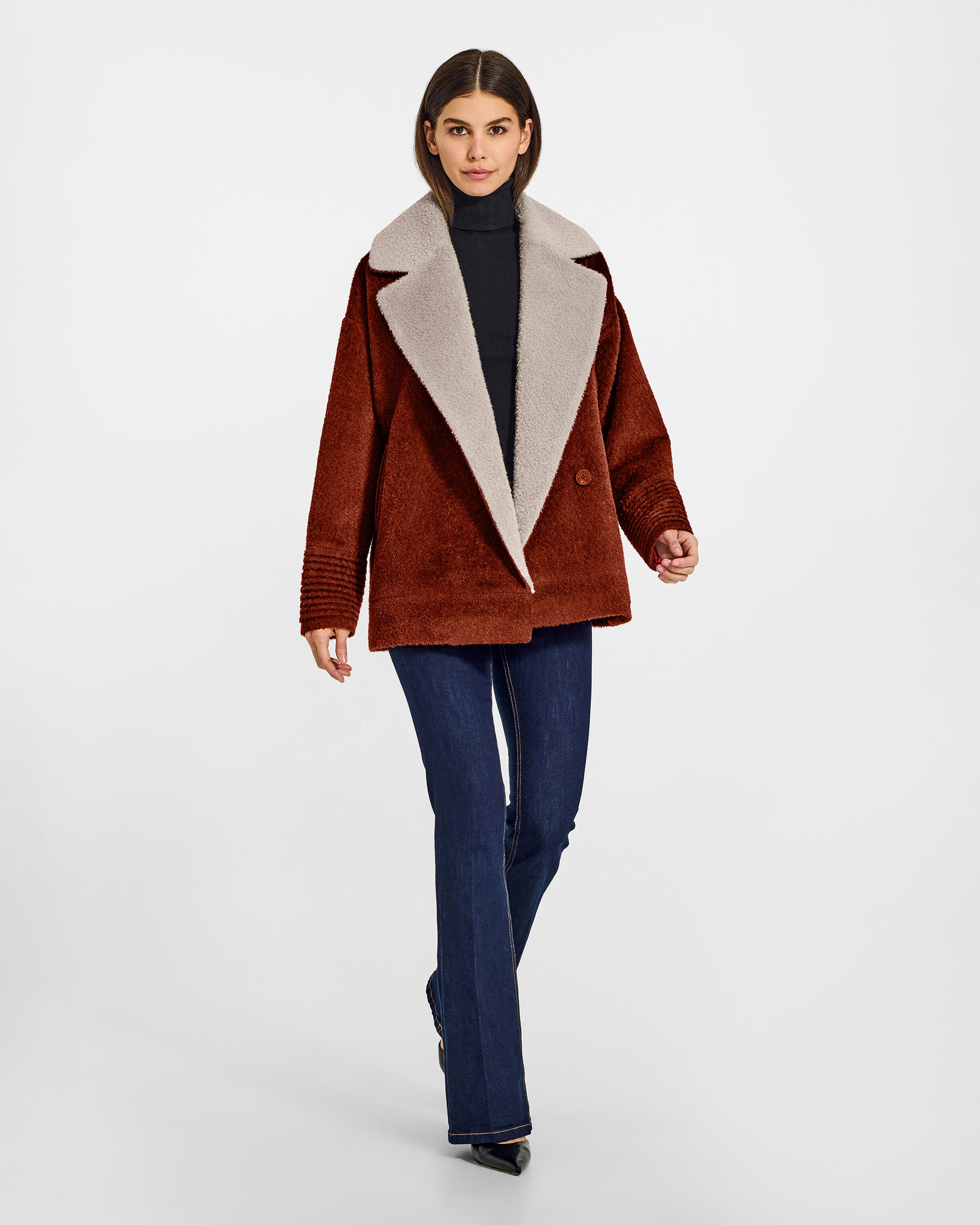 Front view of model wearing a Sentaler rust brown and sand beige aviator jacket made of bouclé alpaca wool, with dropped shoulders, worn buttoned.