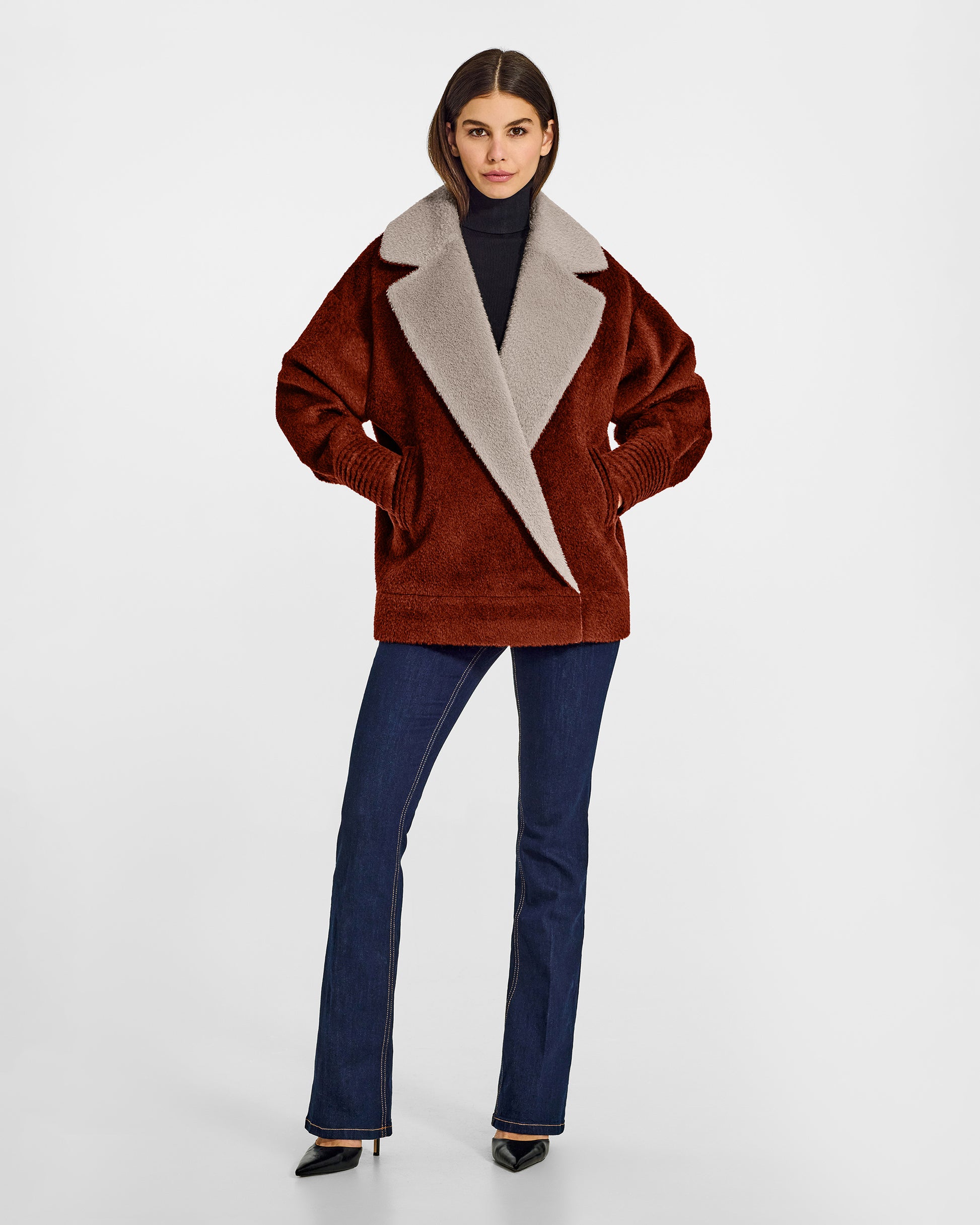 Front view of model wearing a Sentaler rust brown and sand beige aviator jacket made of bouclé alpaca wool, with dropped shoulders, worn buttoned.