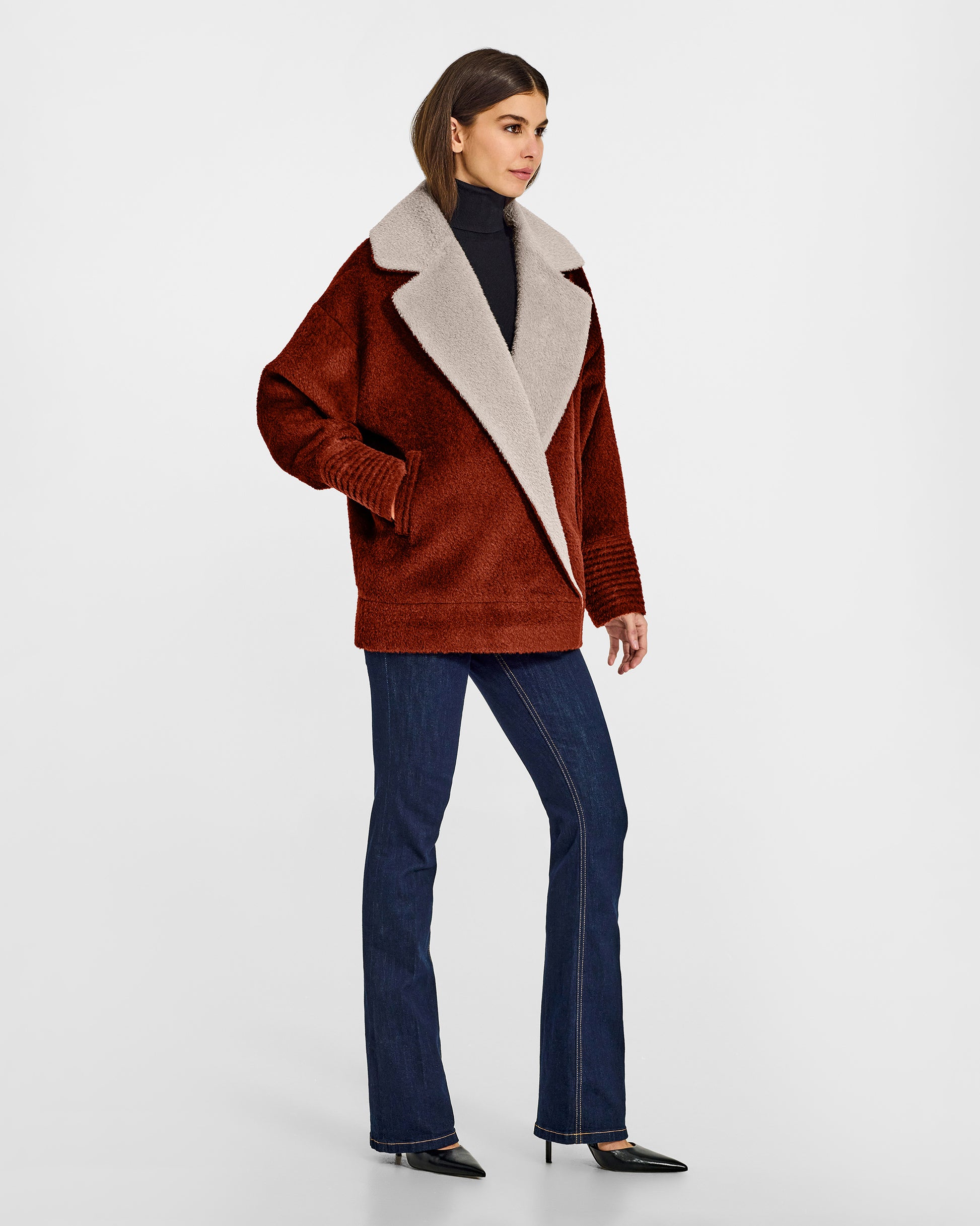 Side view of model wearing a Sentaler rust brown and sand beige aviator jacket made of bouclé alpaca wool, with dropped shoulders, worn buttoned.