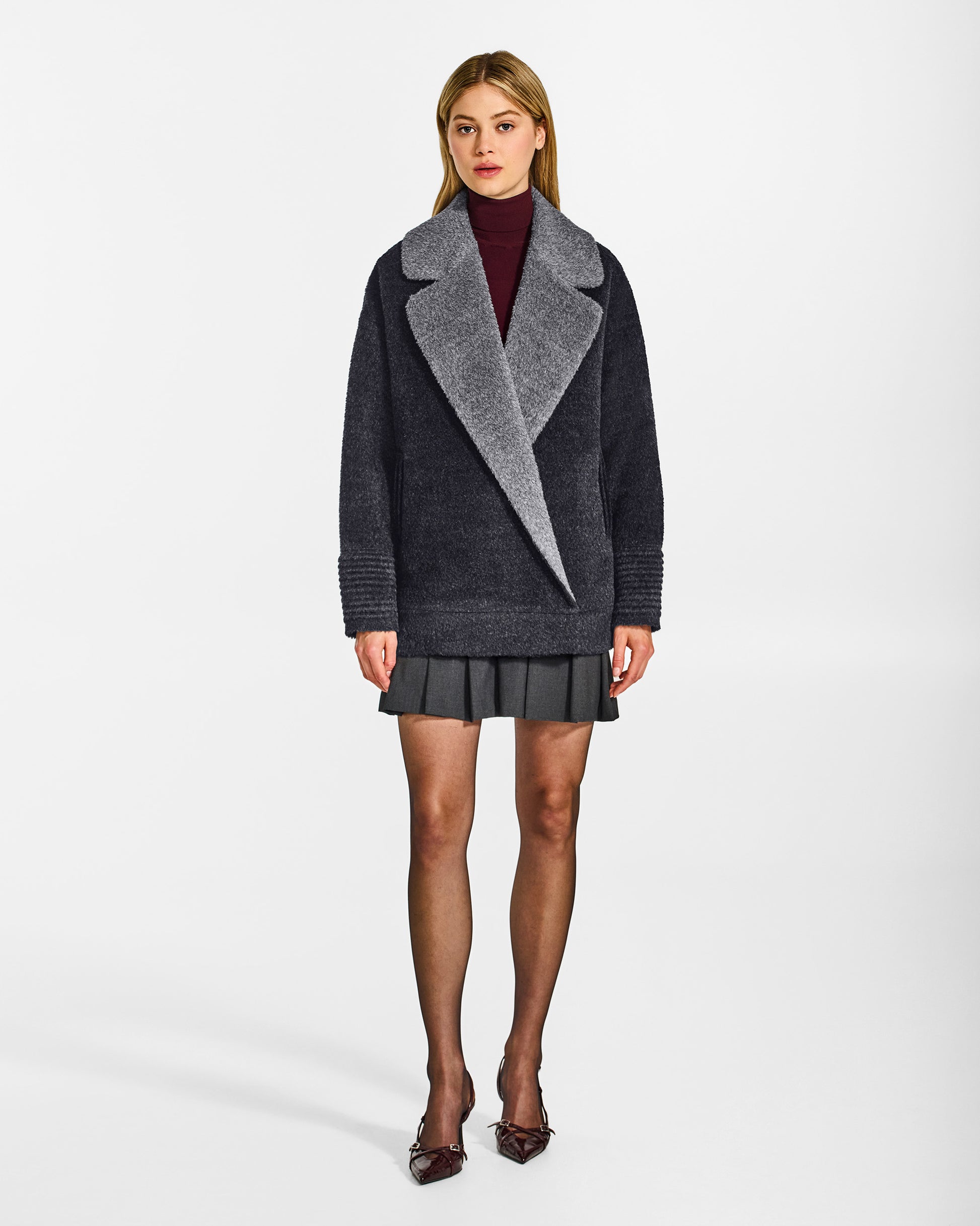 Front view of model wearing a Sentaler charcoal and grey mélange aviator jacket made of bouclé alpaca wool, with dropped shoulders, worn buttoned.