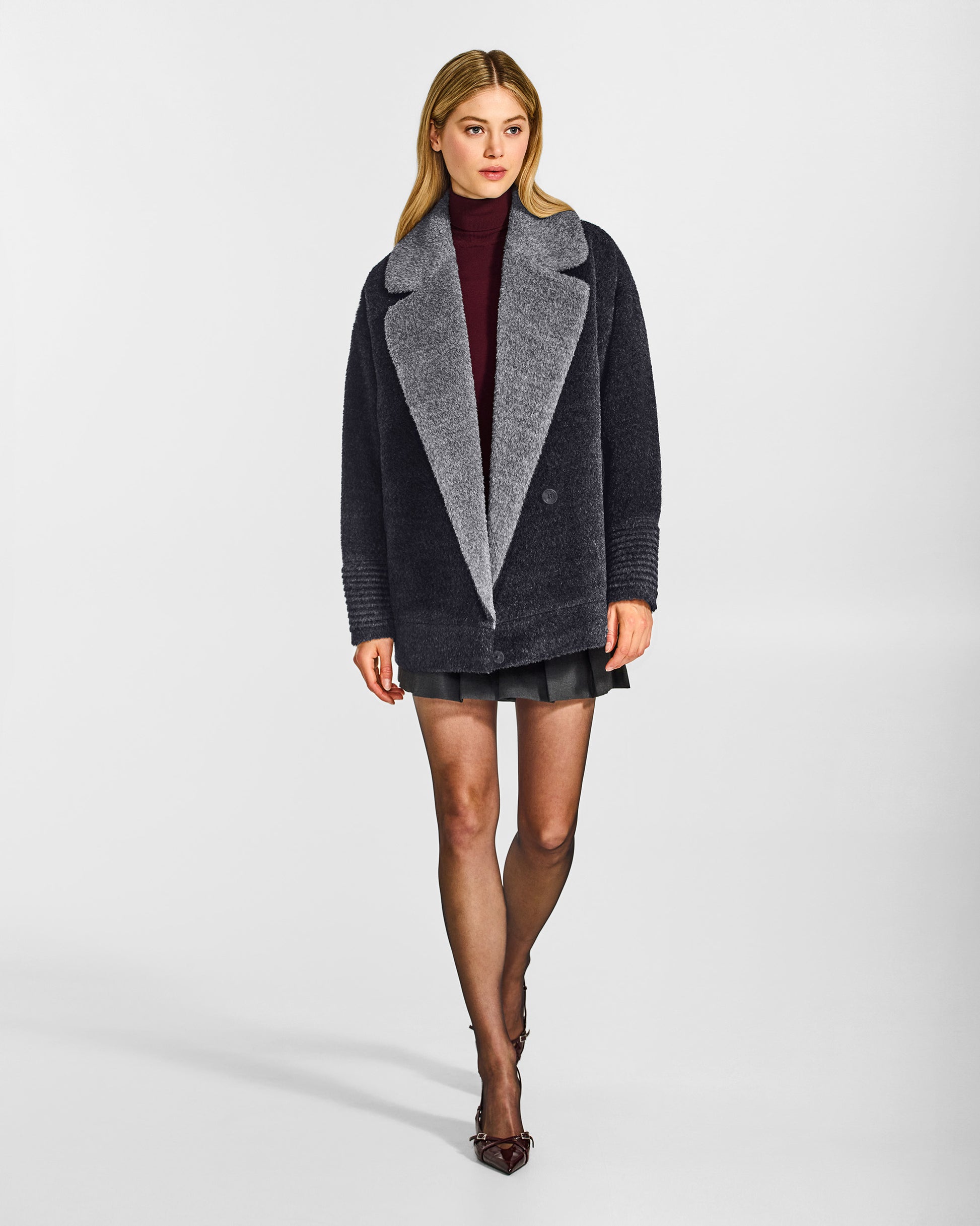 Front view of model wearing a Sentaler charcoal and grey mélange aviator jacket made of bouclé alpaca wool, with dropped shoulders, worn open.