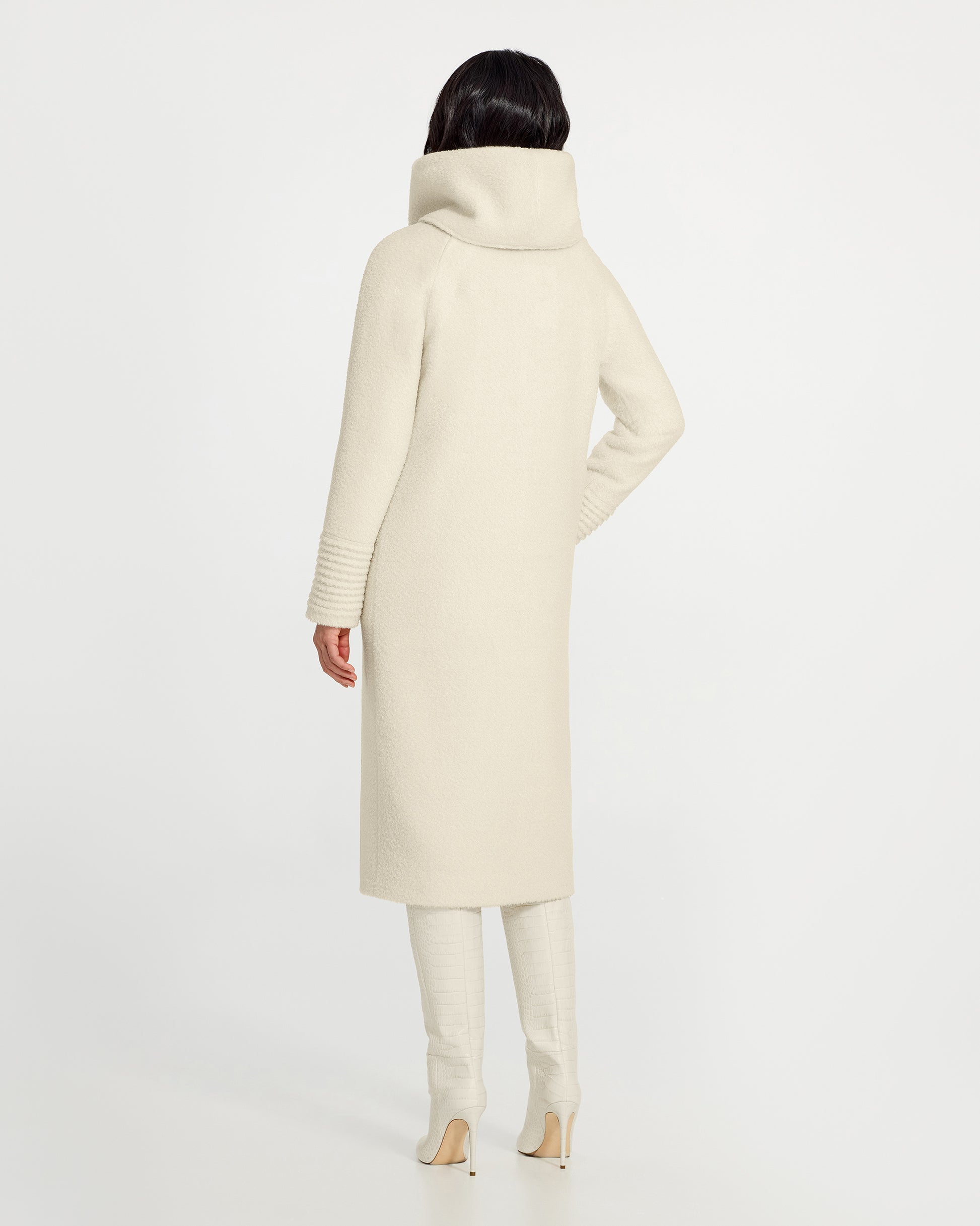 Back view of model wearing a Sentaler long ivory coat made of bouclé alpaca wool, with a hooded collar, worn buttoned.