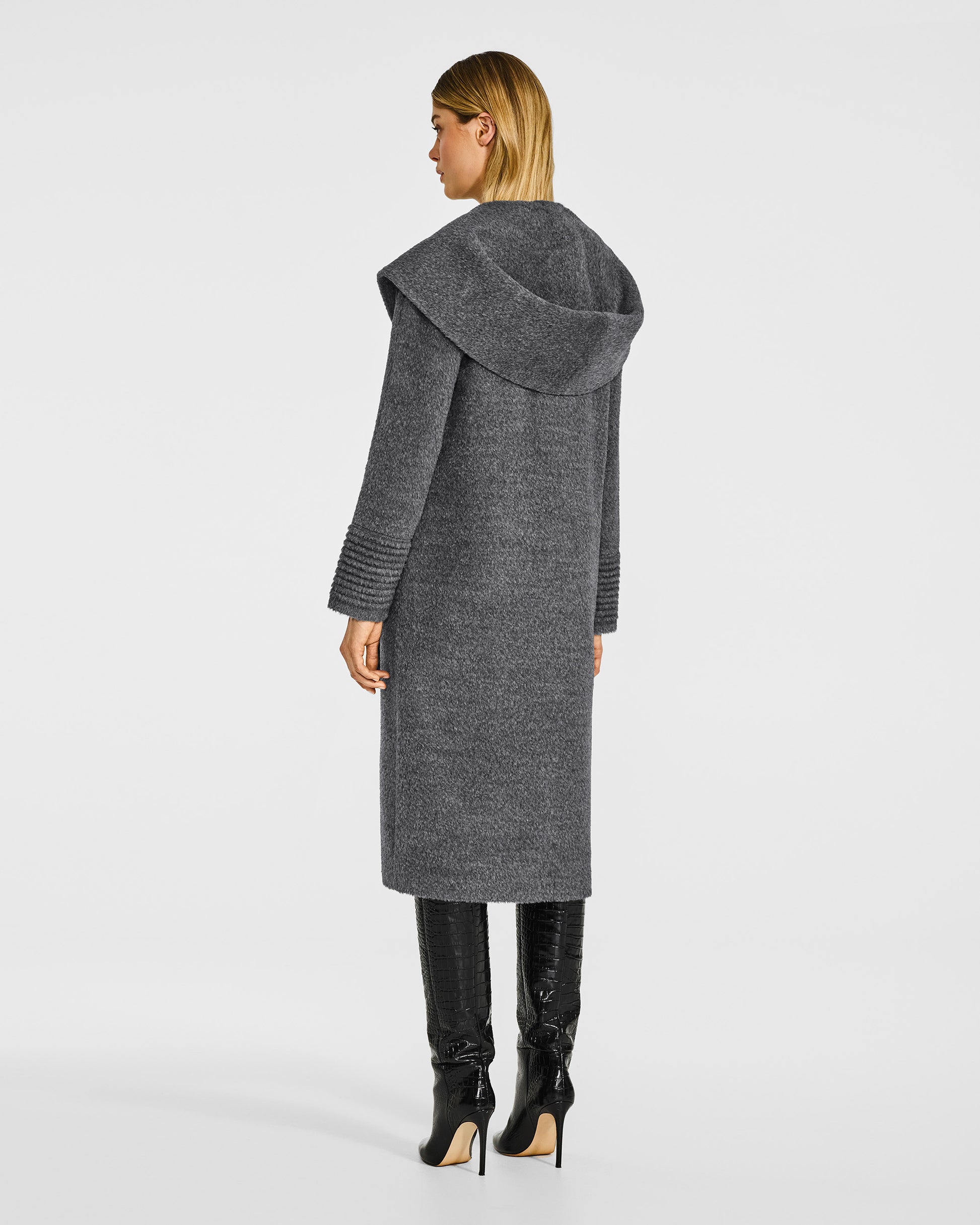 back view of model wearing a Sentaler long grey mélange coat made of bouclé alpaca wool, with a hood collar, worn as a shawl collar.