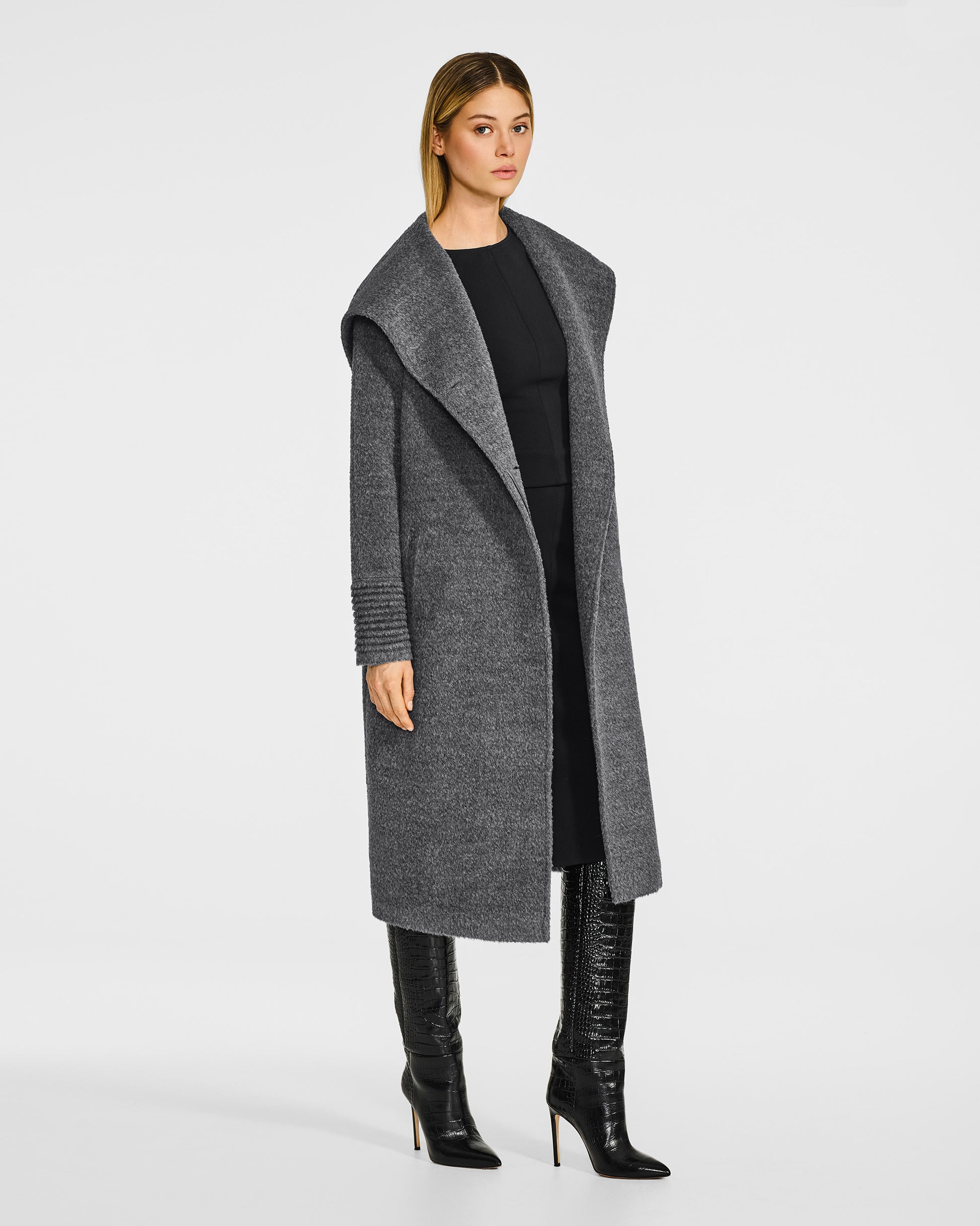 Side view of model wearing a Sentaler long grey mélange coat made of bouclé alpaca wool, with a hood collar, worn open as a shawl collar.