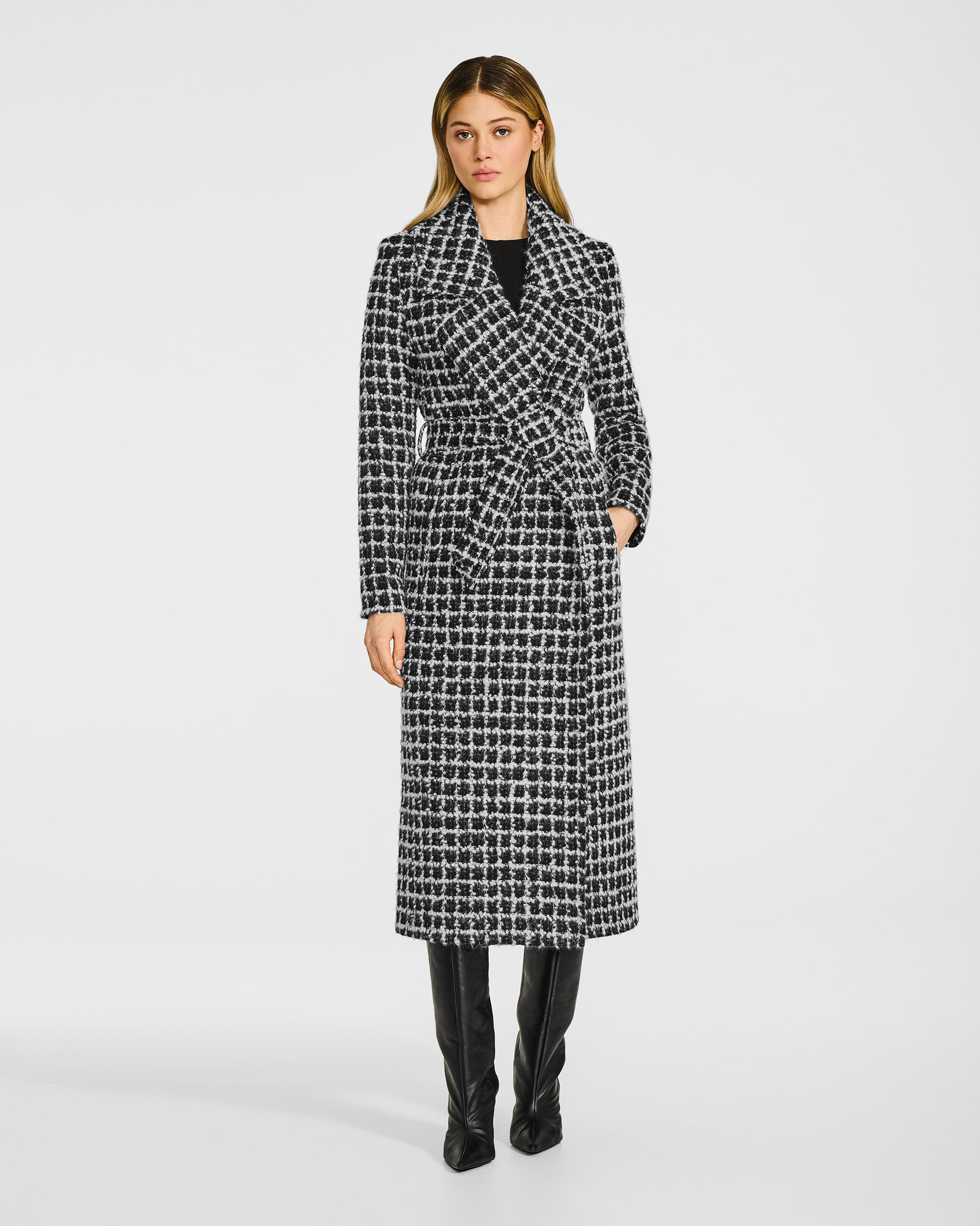 Front view of model wearing a Sentaler black check wrap coat made of suri alpaca wool, with a notched collar, worn belted.