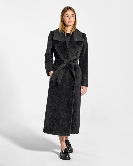 Front view of model wearing a Sentaler black wrap coat made of bouclé alpaca wool, with a notched collar, worn belted.