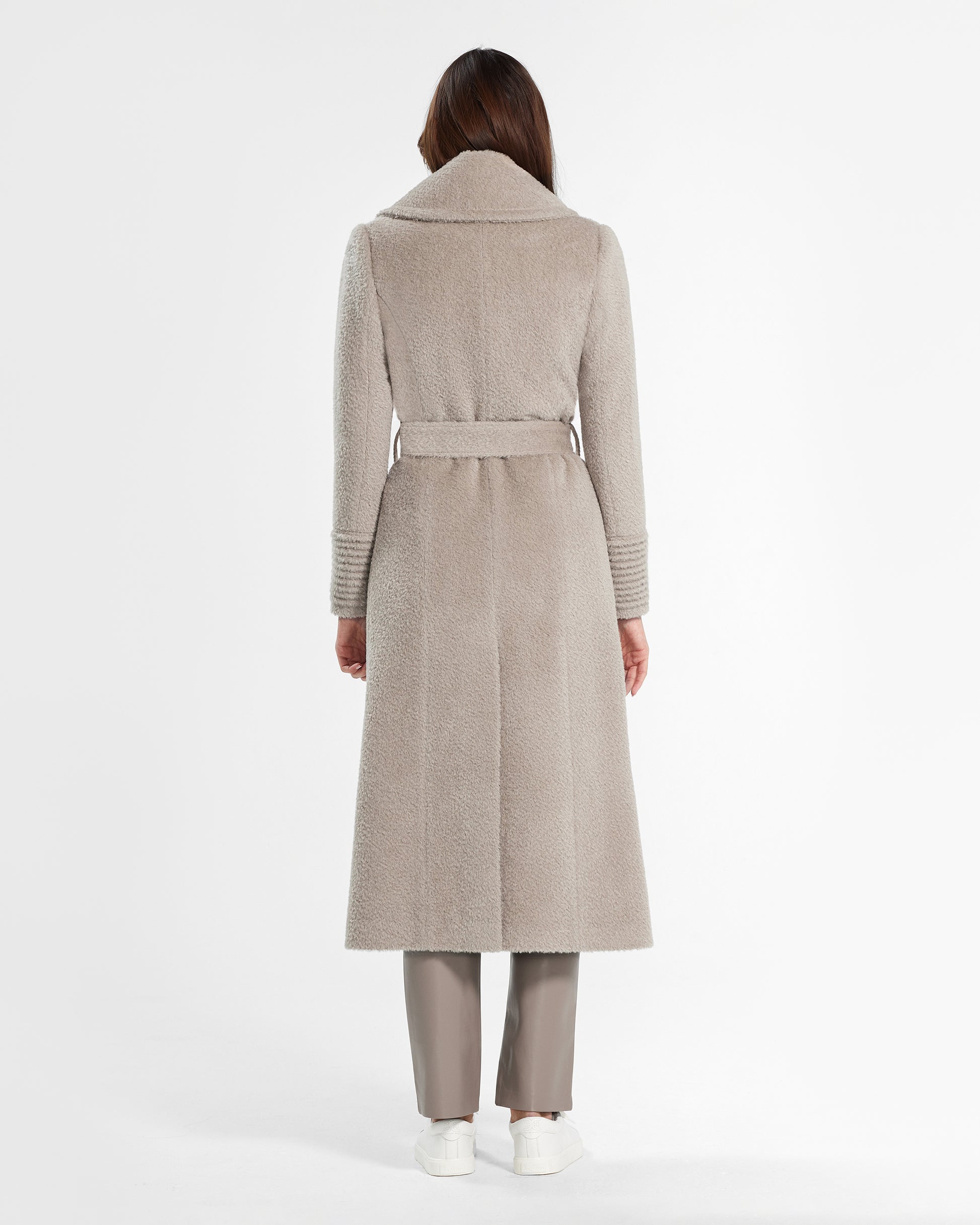 Back view of model wearing a Sentaler sand wrap coat made of bouclé alpaca wool, with a notched collar, worn belted.
