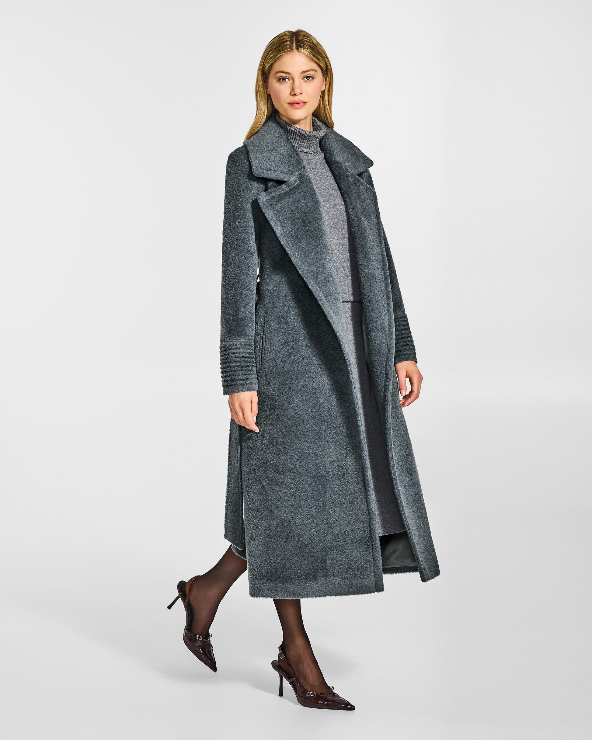 Side view of model wearing a Sentaler graphite grey wrap coat made of bouclé alpaca wool, with a notched collar, worn open.
