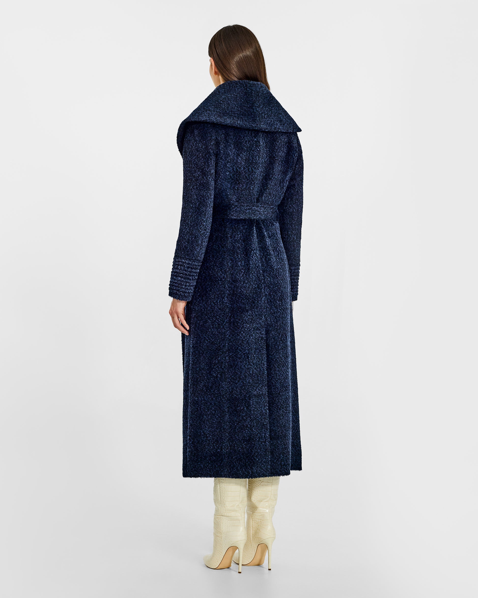 Back view of model wearing a Sentaler midnight blue maxi wrap coat made of bouclé alpaca wool, with a wide shawl collar, worn belted.