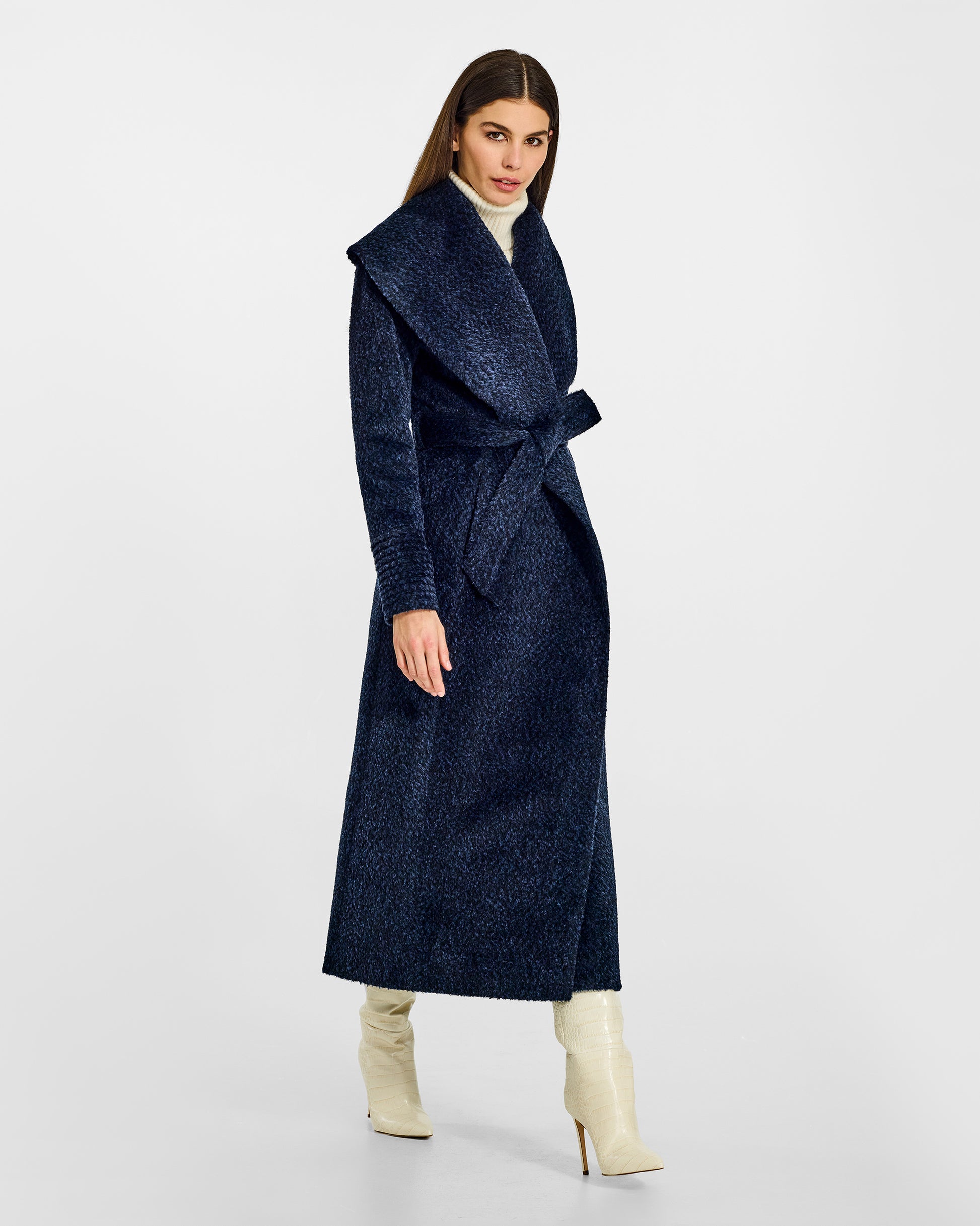 Side view of model wearing a Sentaler midnight blue maxi wrap coat made of bouclé alpaca wool, with a wide shawl collar, worn belted.