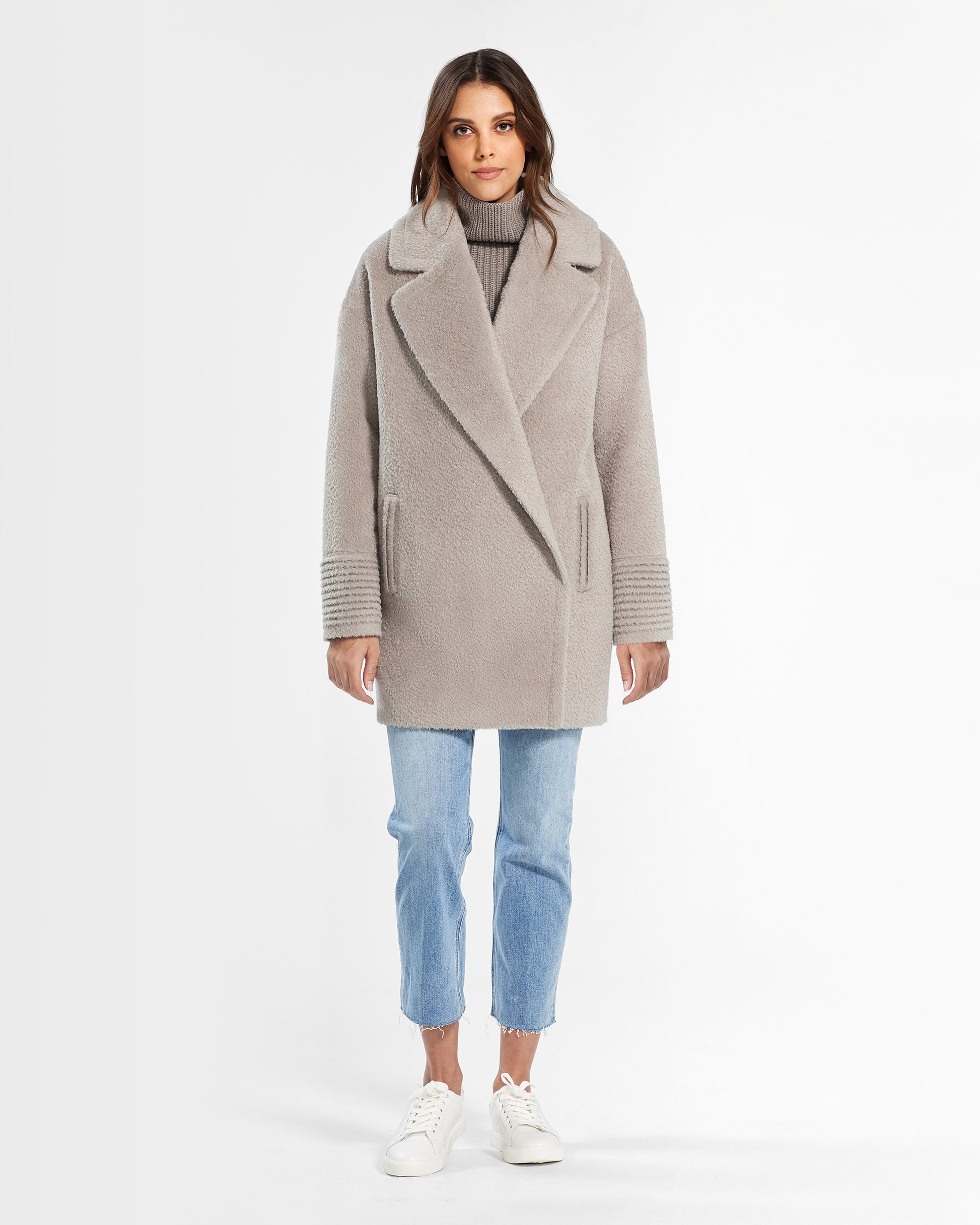 Front view of model wearing a Sentaler mid length sand oversized coat made of bouclé alpaca wool, worn buttoned.