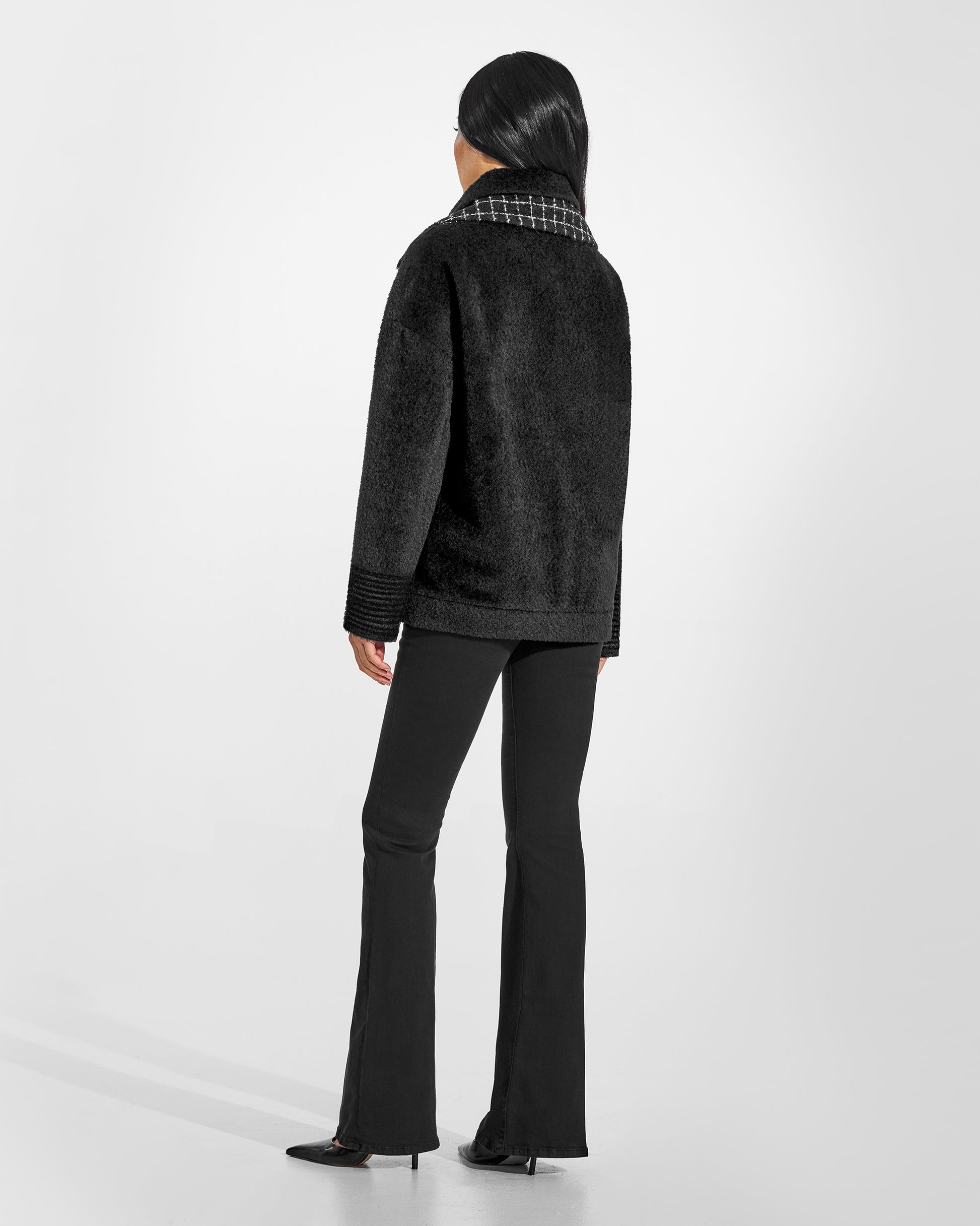Back view of model wearing a Sentaler black bomber jacket made of bouclé alpaca wool, with double collar, worn buttoned.