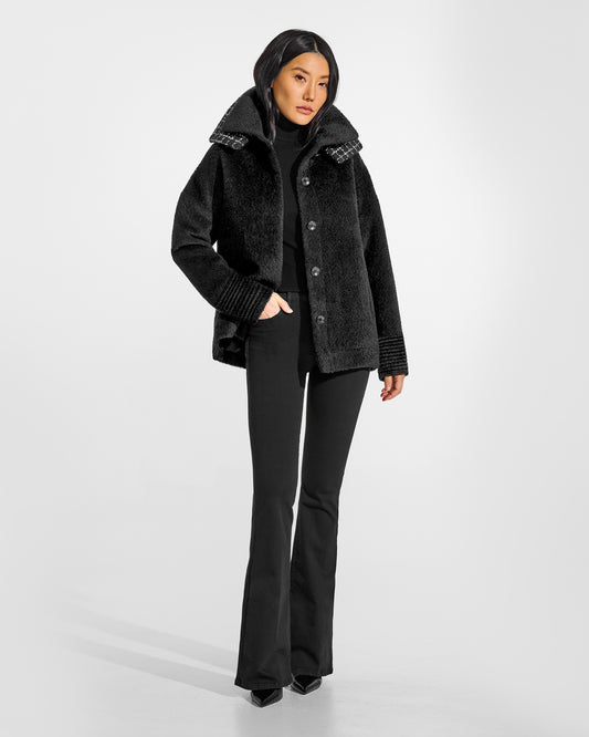 Front view of model wearing a Sentaler black bomber jacket made of bouclé alpaca wool, with double collar, worn open.