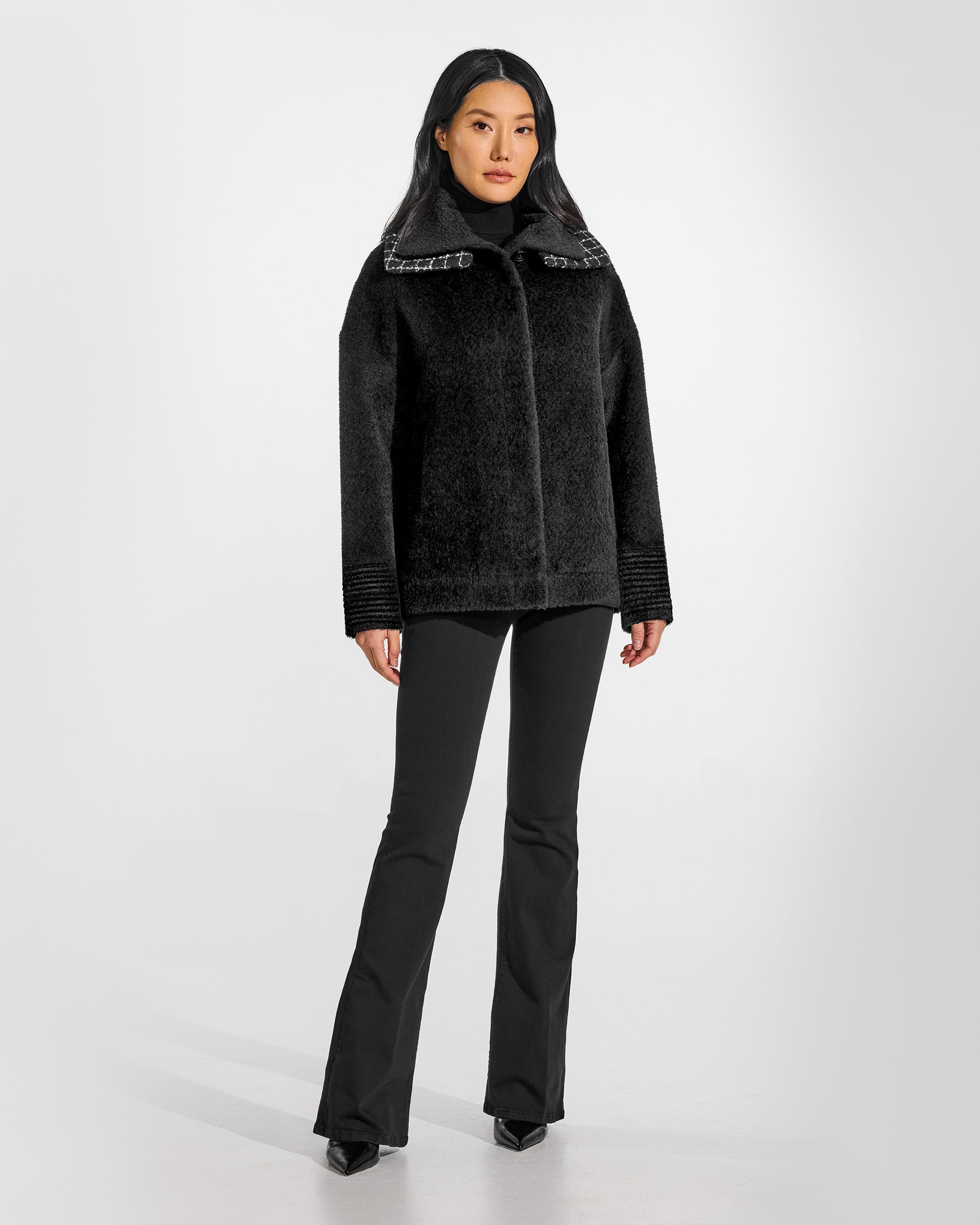 Front view of model wearing a Sentaler black bomber jacket made of bouclé alpaca wool, with double collar, worn buttoned.