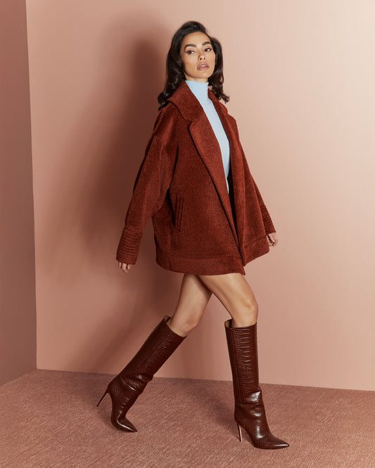 Side view of model wearing a Sentaler rust aviator jacket made of bouclé alpaca wool, with dropped shoulders, worn open.