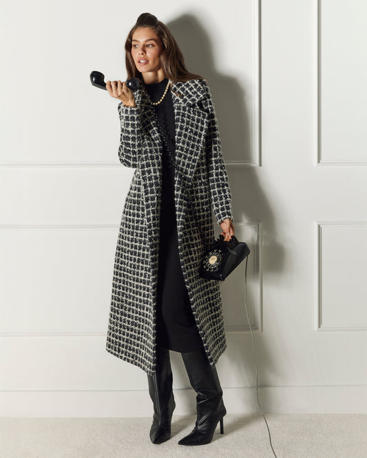 Front view of model wearing a Sentaler black check wrap coat made of suri alpaca wool, with a notched collar, worn open.