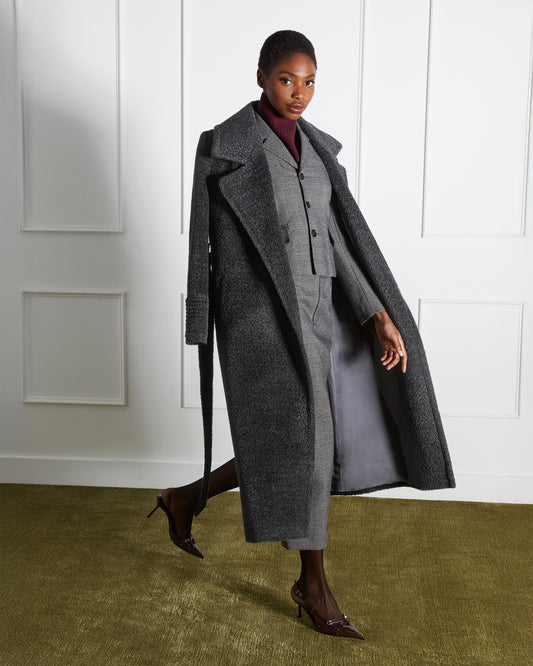 Side view of model wearing a Sentaler graphite wrap coat made of bouclé alpaca wool, with a notched collar, worn open.