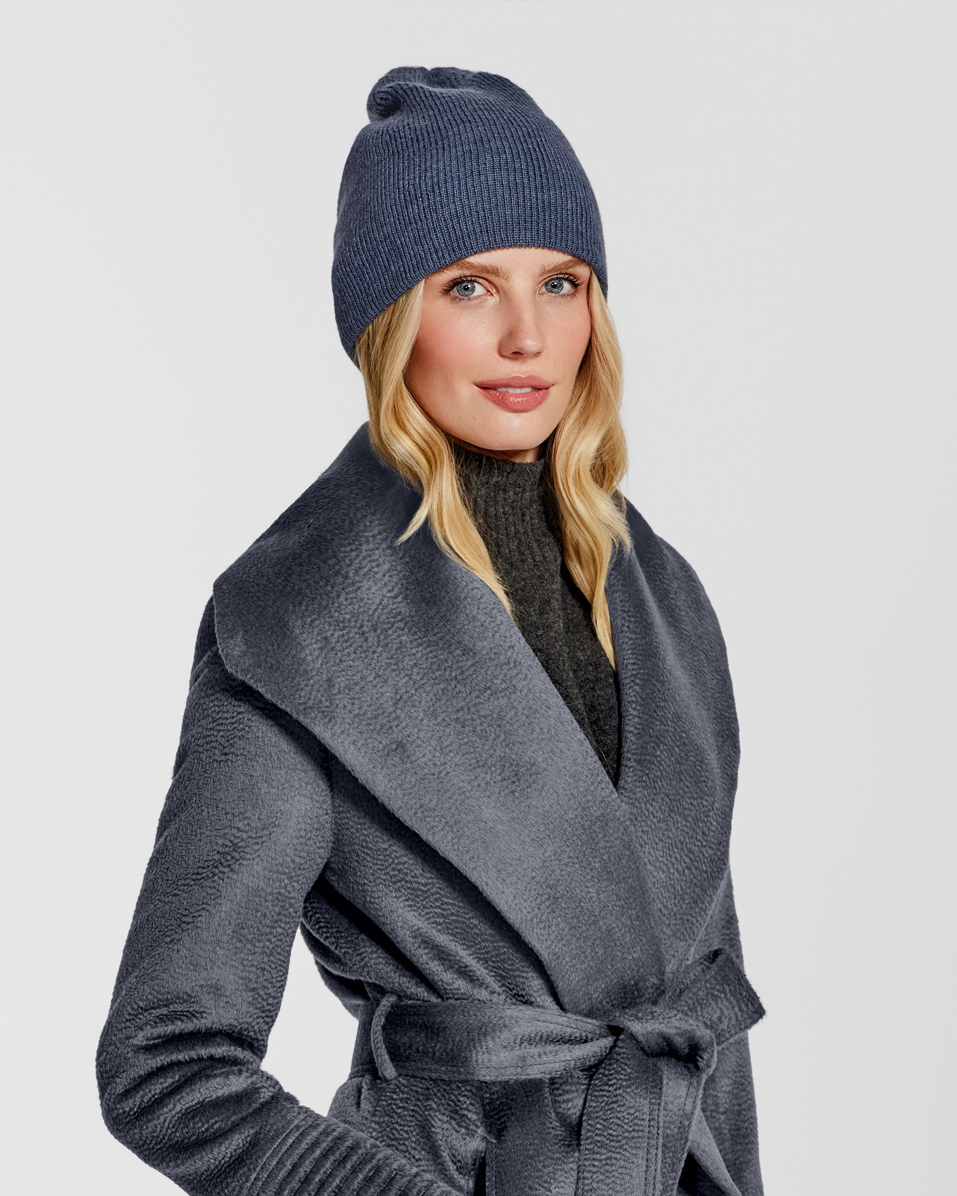 Side close up view of model wearing Sentaler's classic graphite beanie, made of baby alpaca yarn, paired with a graphite coat.