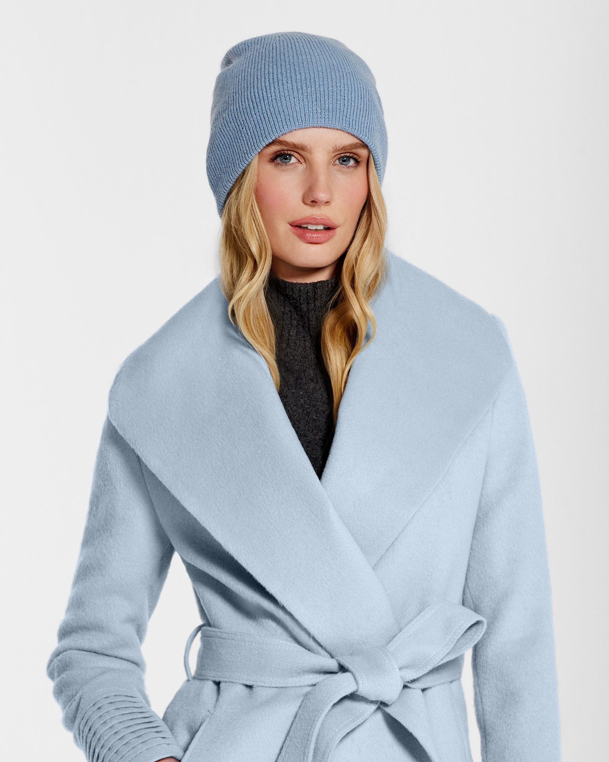 Front close up view of model wearing Sentaler's classic powder blue beanie, made of baby alpaca yarn, paired with a powder blue coat.