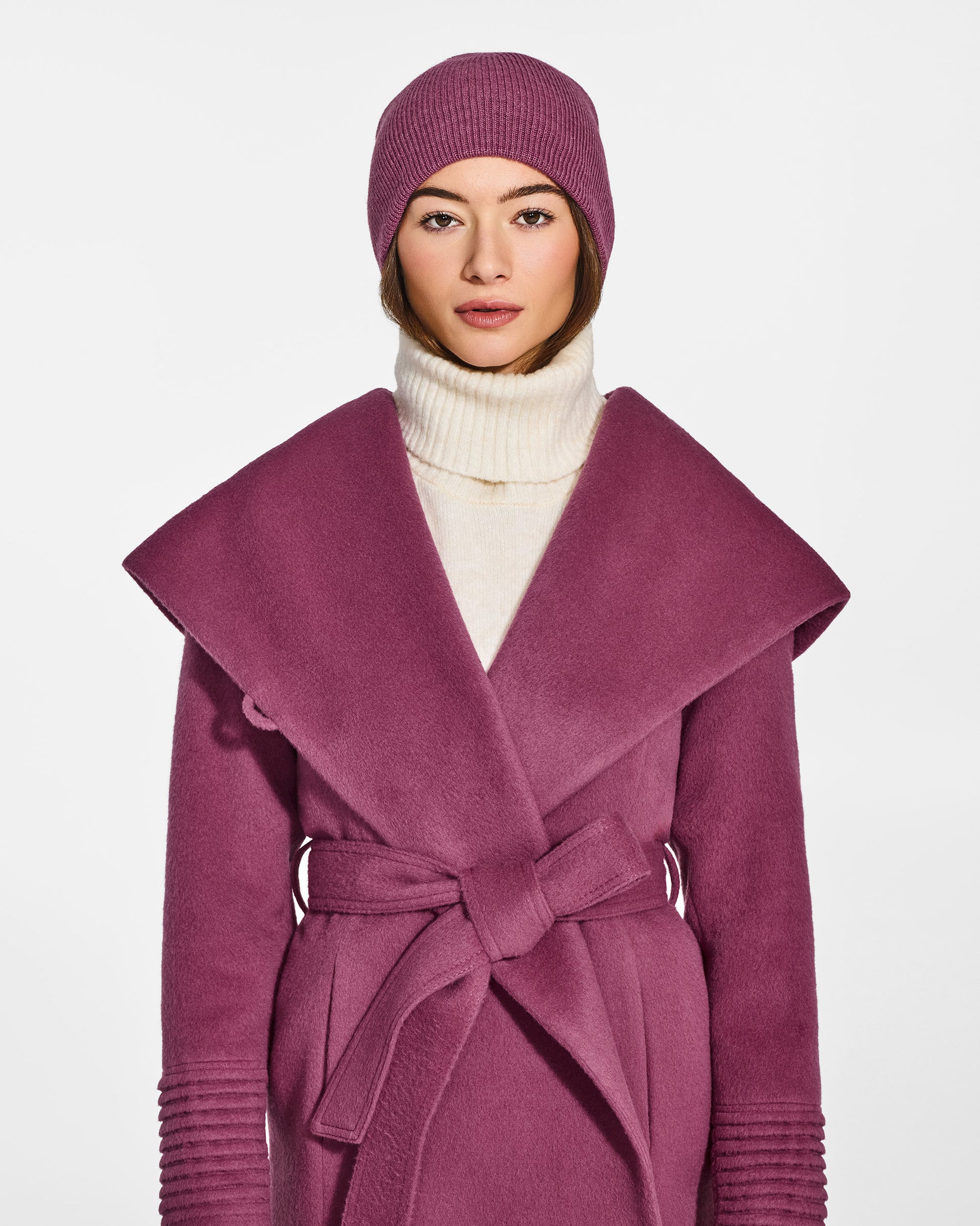 Front view of model wearing Sentaler's classic mauve pink beanie, made of baby alpaca yarn, paired with a mauve pink coat.