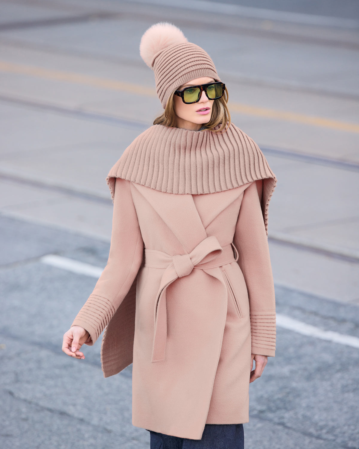 Front view of model wearing Sentaler's signature blush pink ribbed hat, scarf, and gloves, paired with a matching blush pink coat.