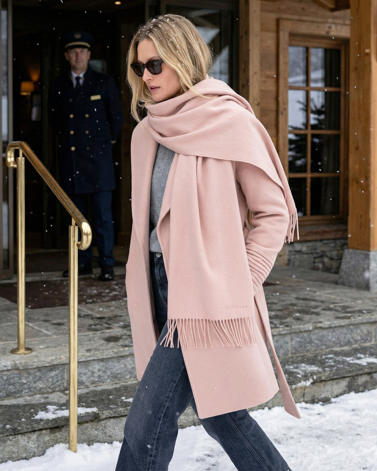 Front view of model wearing a Sentaler mid length blush pink coat made of baby alpaca wool, with a shawl collar, worn belted.