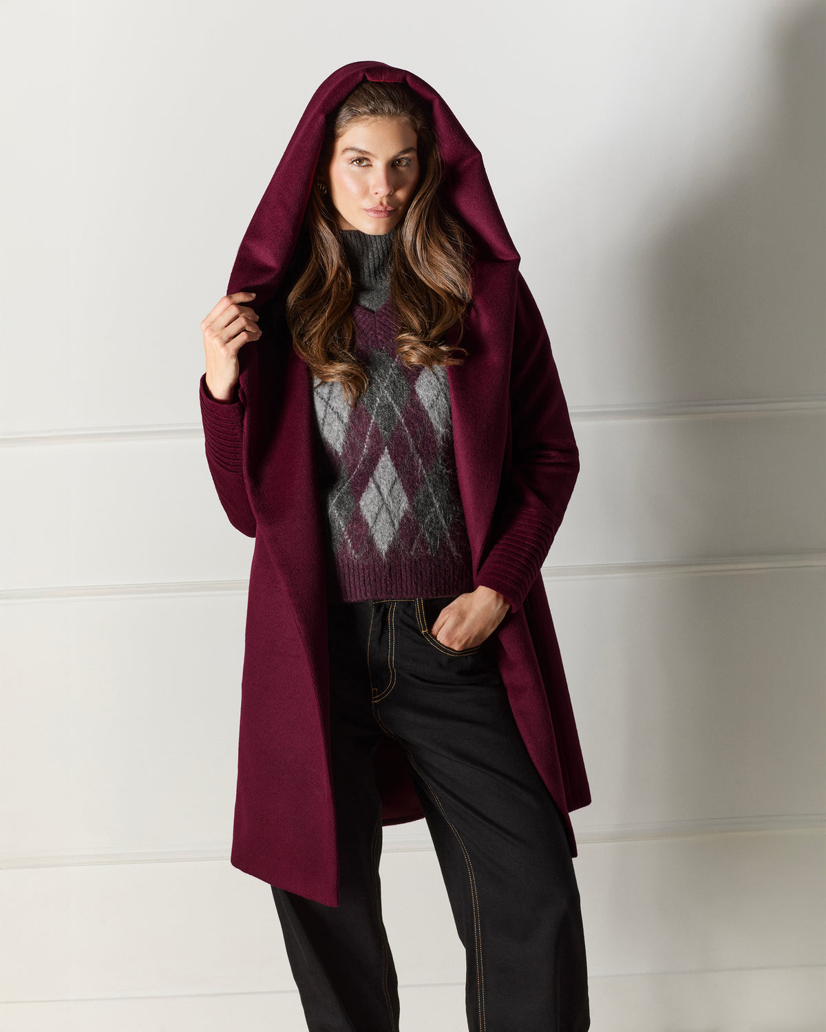 Front view of model wearing a Sentaler mid length cherry lacquer coat made of baby alpaca wool, with a hooded collar, worn open.