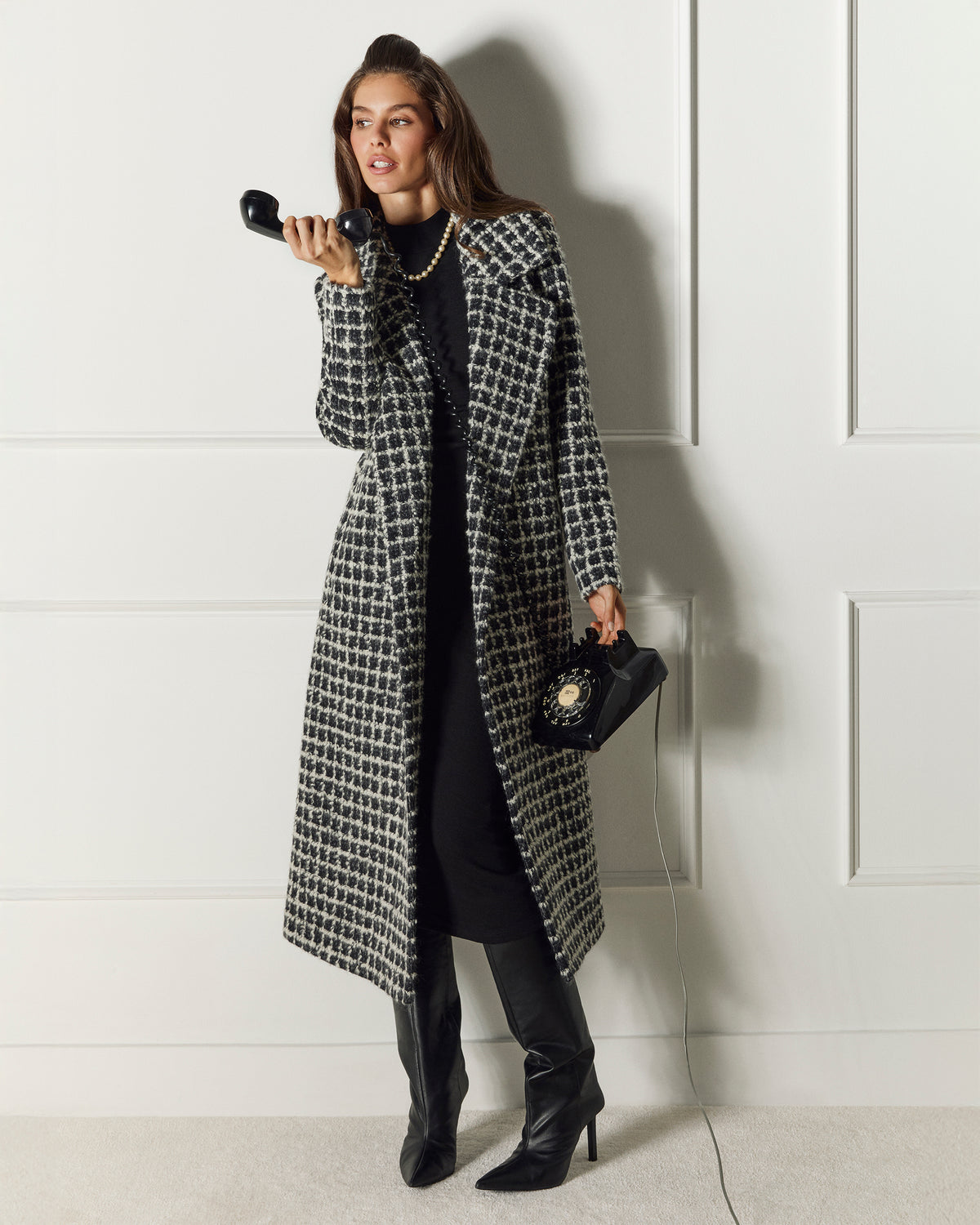 Front view of model wearing a Sentaler black check wrap coat made of suri alpaca wool, with a notched collar, worn open.