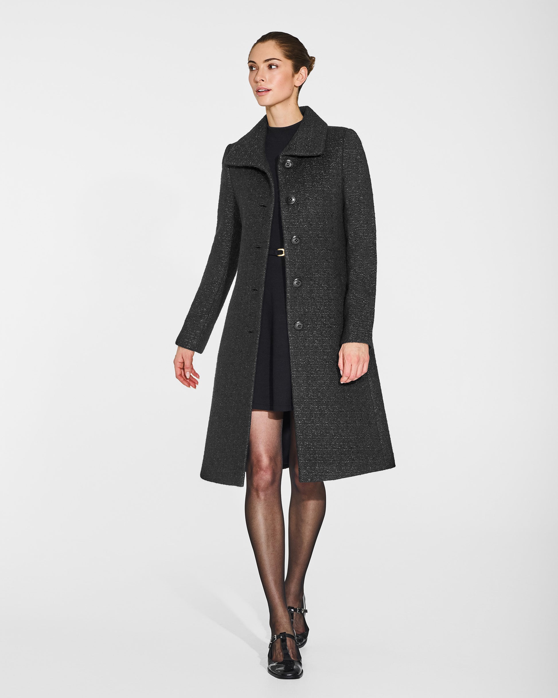 Front view of model in Sentaler black glittered A-line coat with empire waist in tweed suri alpaca, open.