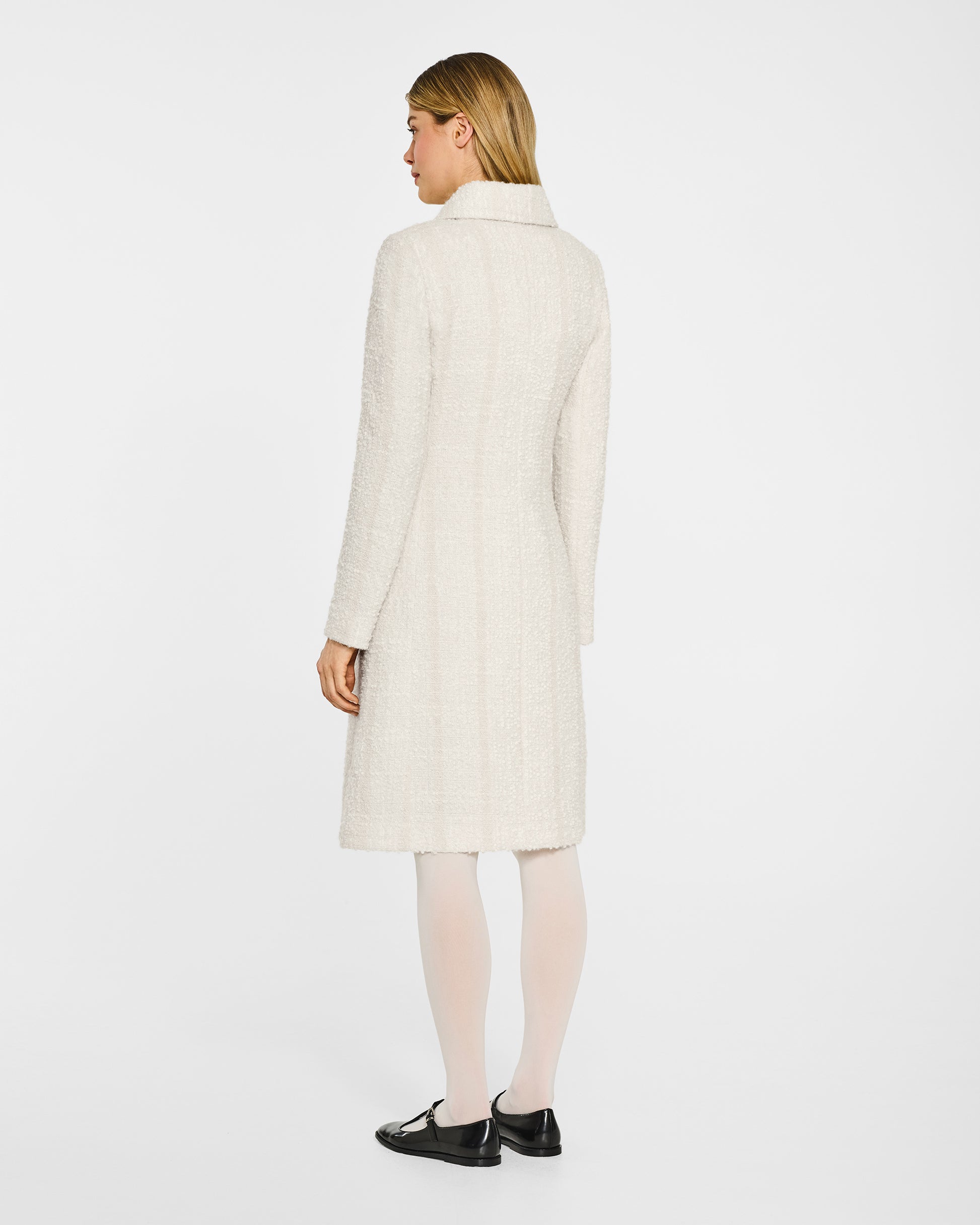 Back view of model wearing a Sentaler ivory glittered A-line coat made of tweed suri alpaca wool, worn buttoned.
