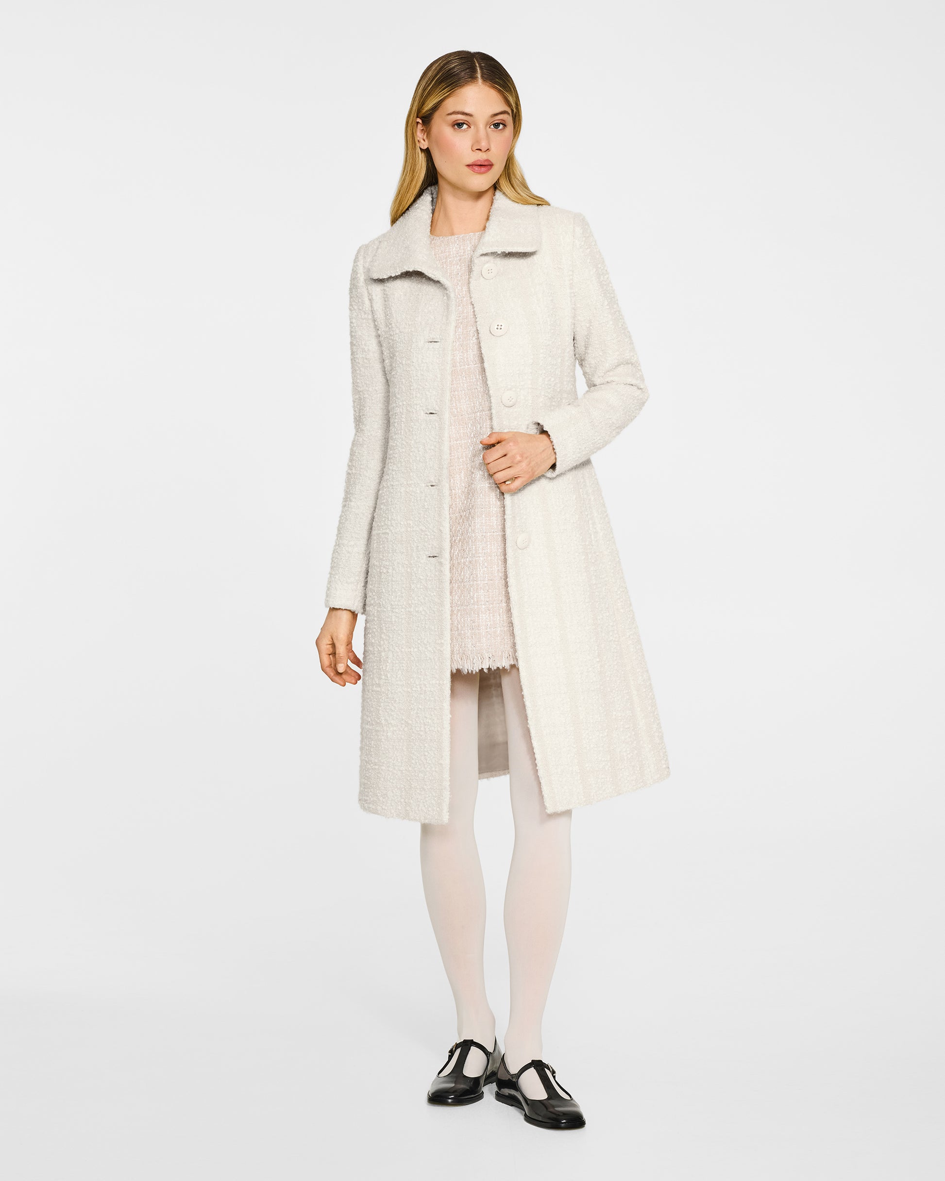 Front view of model wearing a Sentaler ivory glittered A-line coat made of tweed suri alpaca wool, worn open.