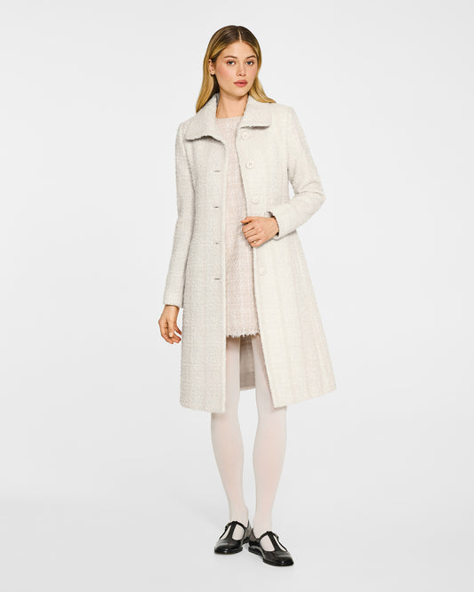 Front view of model wearing a Sentaler ivory glittered A-line coat made of tweed suri alpaca wool, worn open.